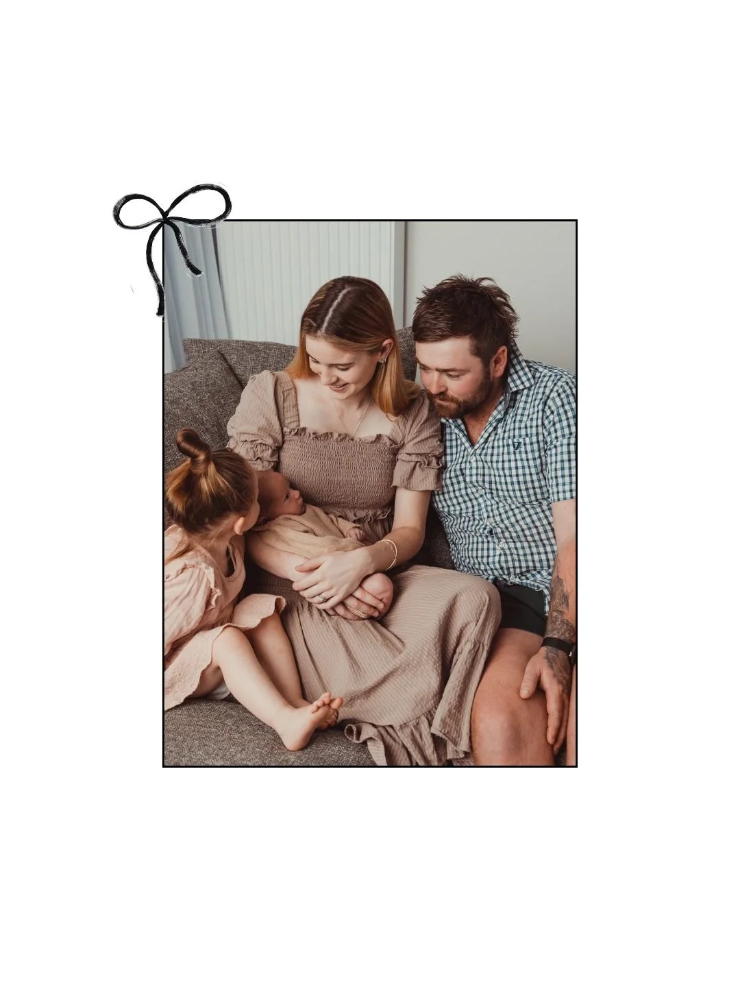 Family sitting on sofa with a newborn baby, a young girl looking at the baby, parents smiling and looking at the baby.