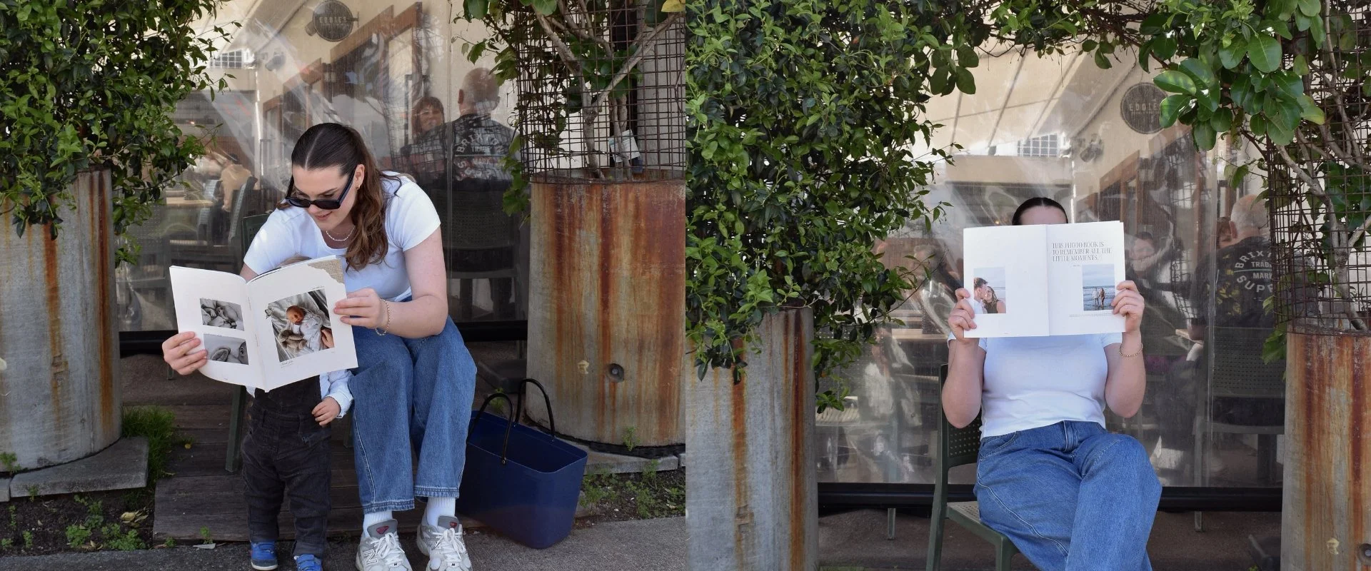 Two women and a child reading outside at a restaurant or cafe with large potted plants and outdoor seating. The woman on the left is seated, and the woman on the right is sitting on a chair, holding a menu up to her face, obscuring her identity.