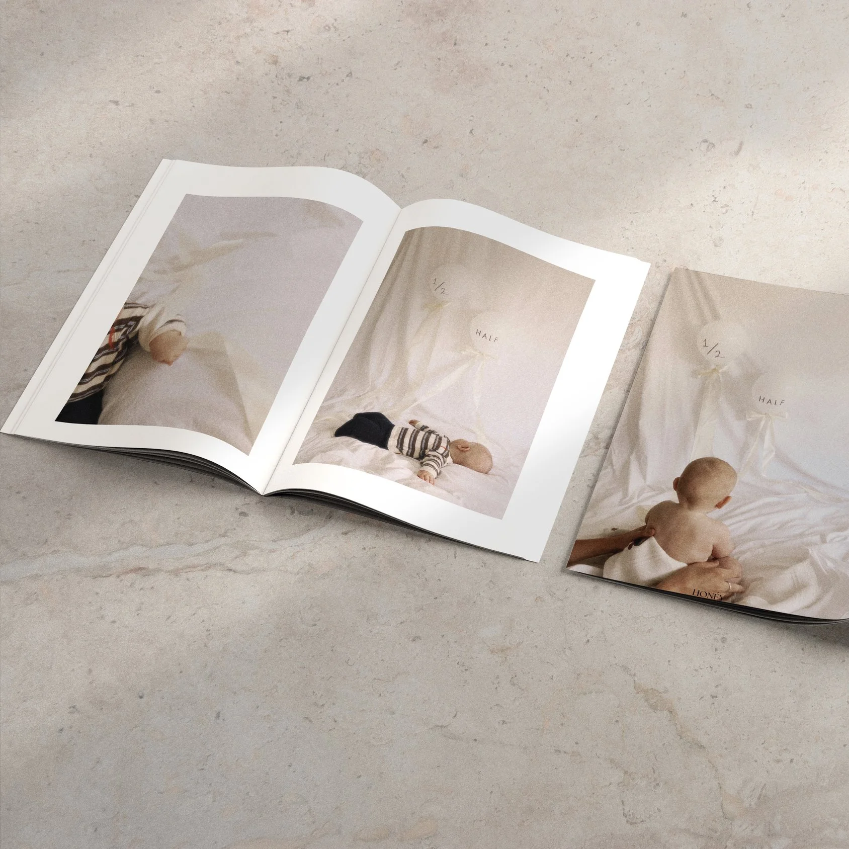 Open photo album with images of a baby lying and crawling on a white bed with a white backdrop, labeled '1/2 HALF.'