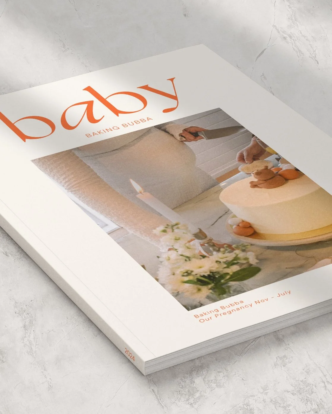 A magazine titled 'baby' with a cover photo of a pregnant woman baking cookies, featuring a cake, flowers, and candles on a table.