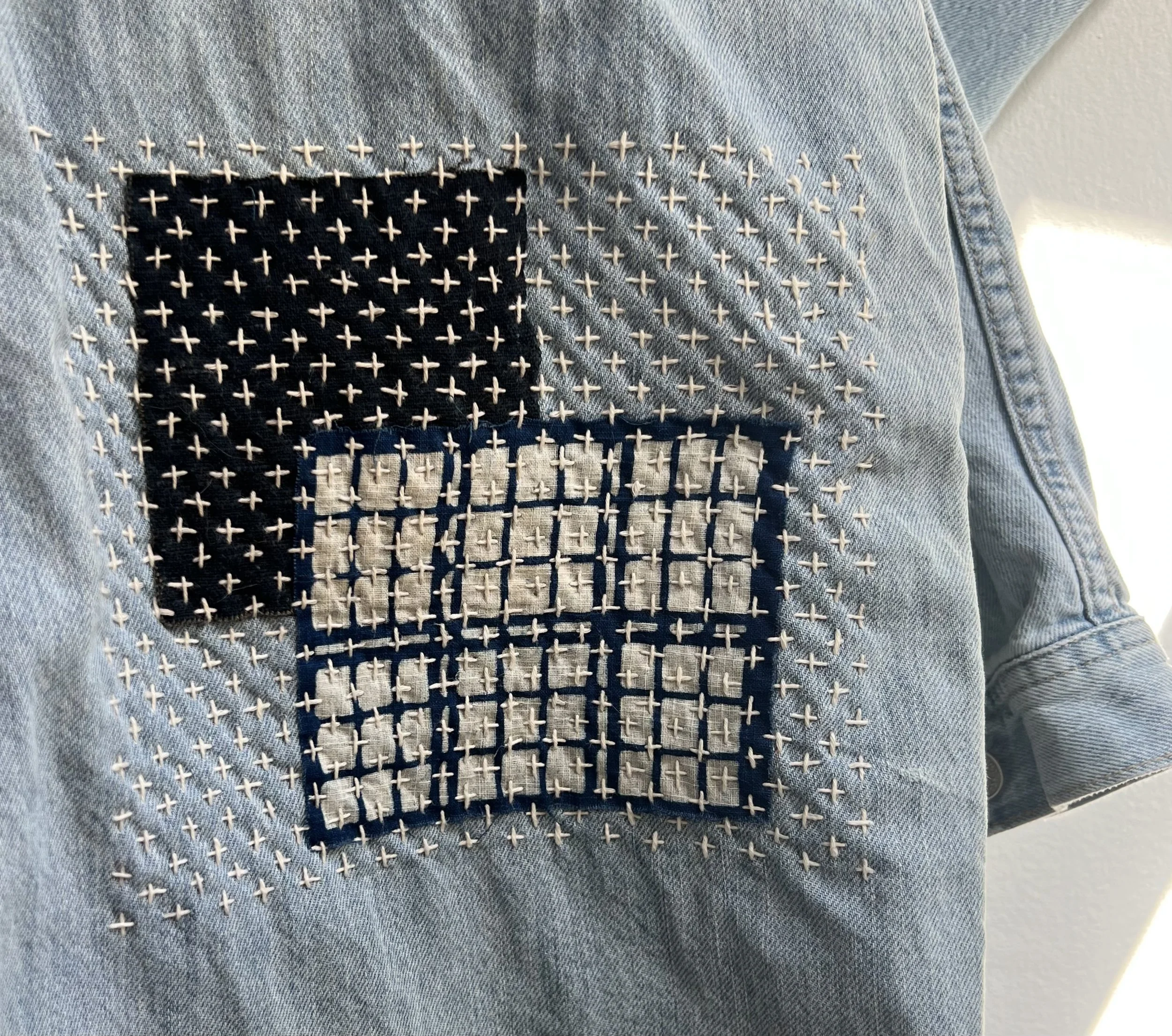 Mending pair of pants with plus sashiko-style stitching over patches