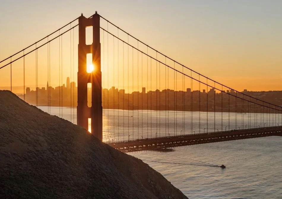 Sun rising behind suspension bridge representing how Ordinance brings clarity to complex reinsurance pricing models.