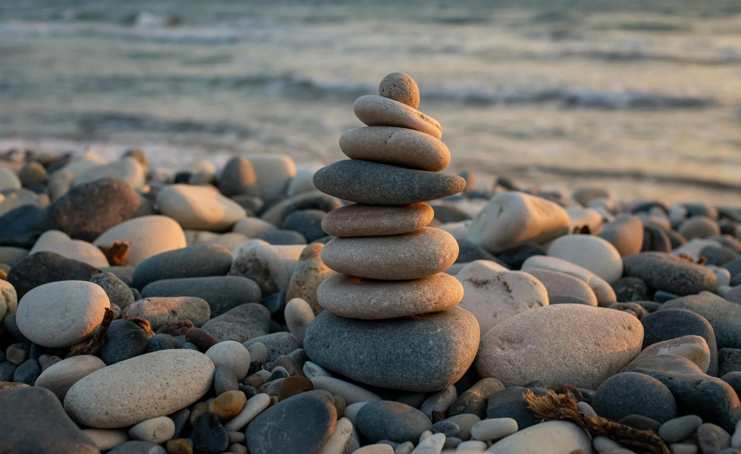 Balanced stone stack by the shoreline representing structured, reliable loss reserving analysis offered by Ordinance.