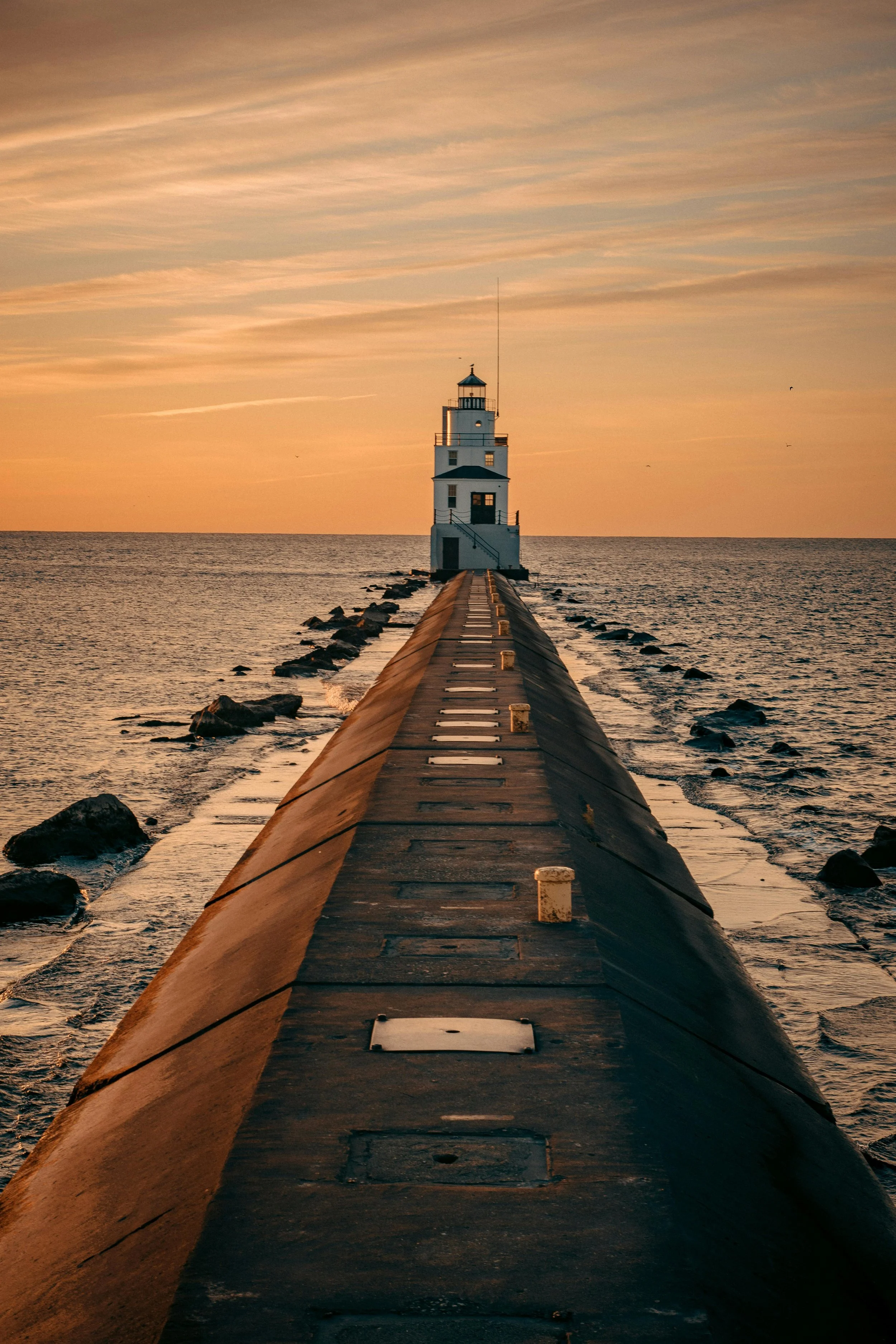 Lighthouse at the end of a pier, representing dependable actuarial guidance and a clear path toward informed decisions.