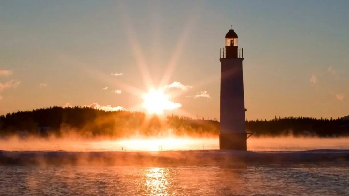 Lighthouse at sunrise guiding ships, reflecting how actuarial insights support informed insurance and risk decisions.