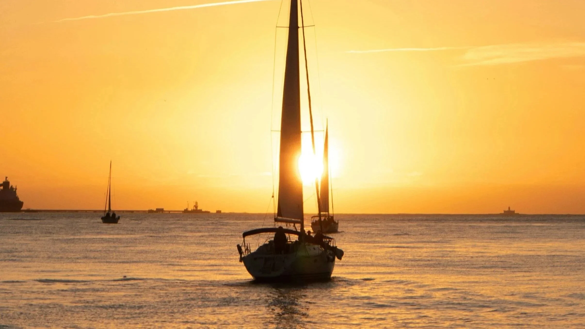 Sailboat navigating calm waters at sunset, representing steady actuarial guidance through complex insurance decisions.