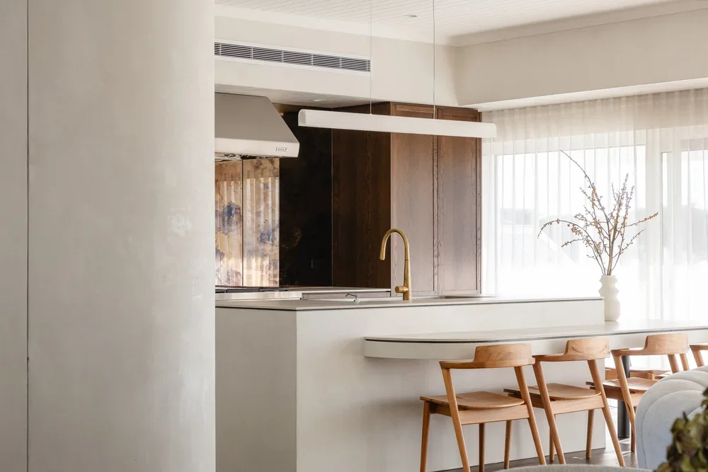 Modern kitchen with a white microcement island, vent hood and walls.