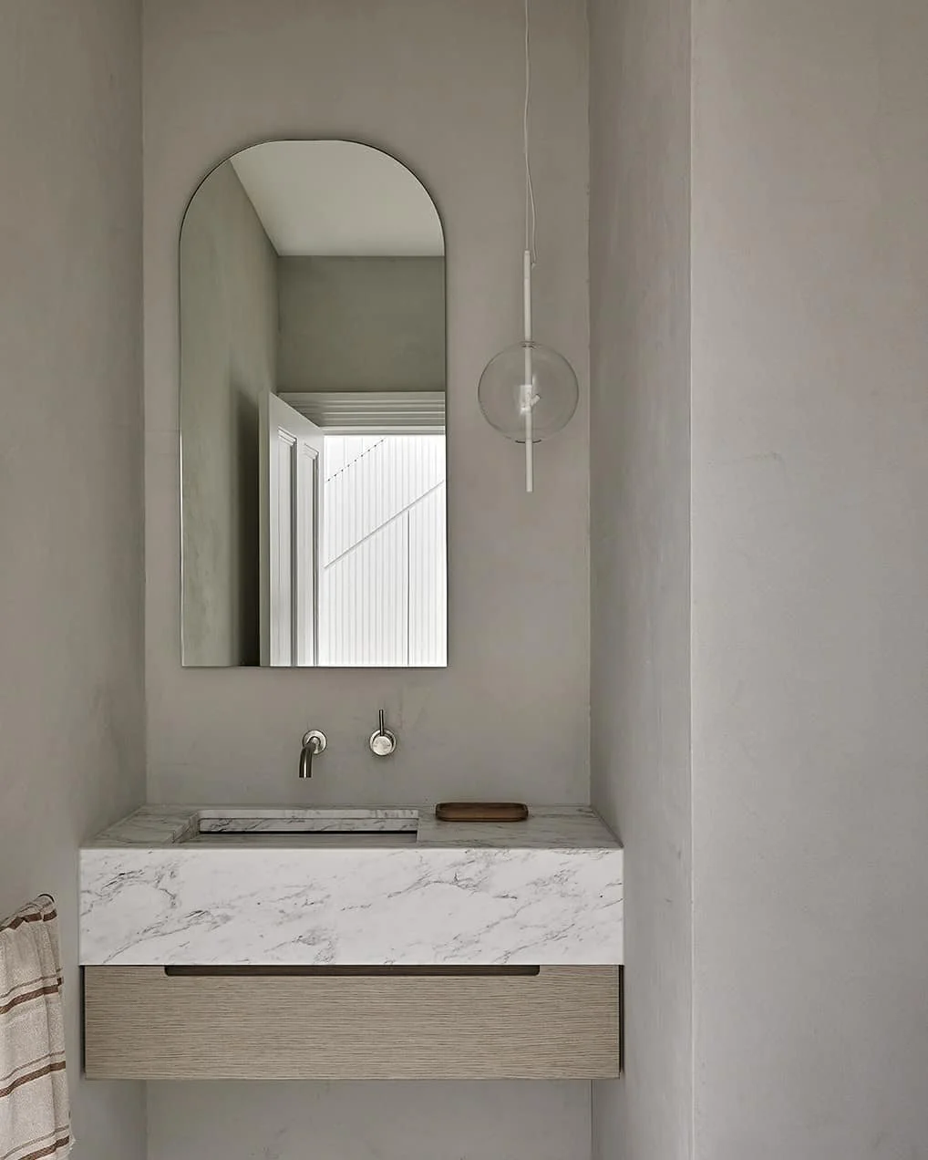 Minimalist bathroom with a marble countertop perfectly complemented by handcrafted microcement walls and ceiling