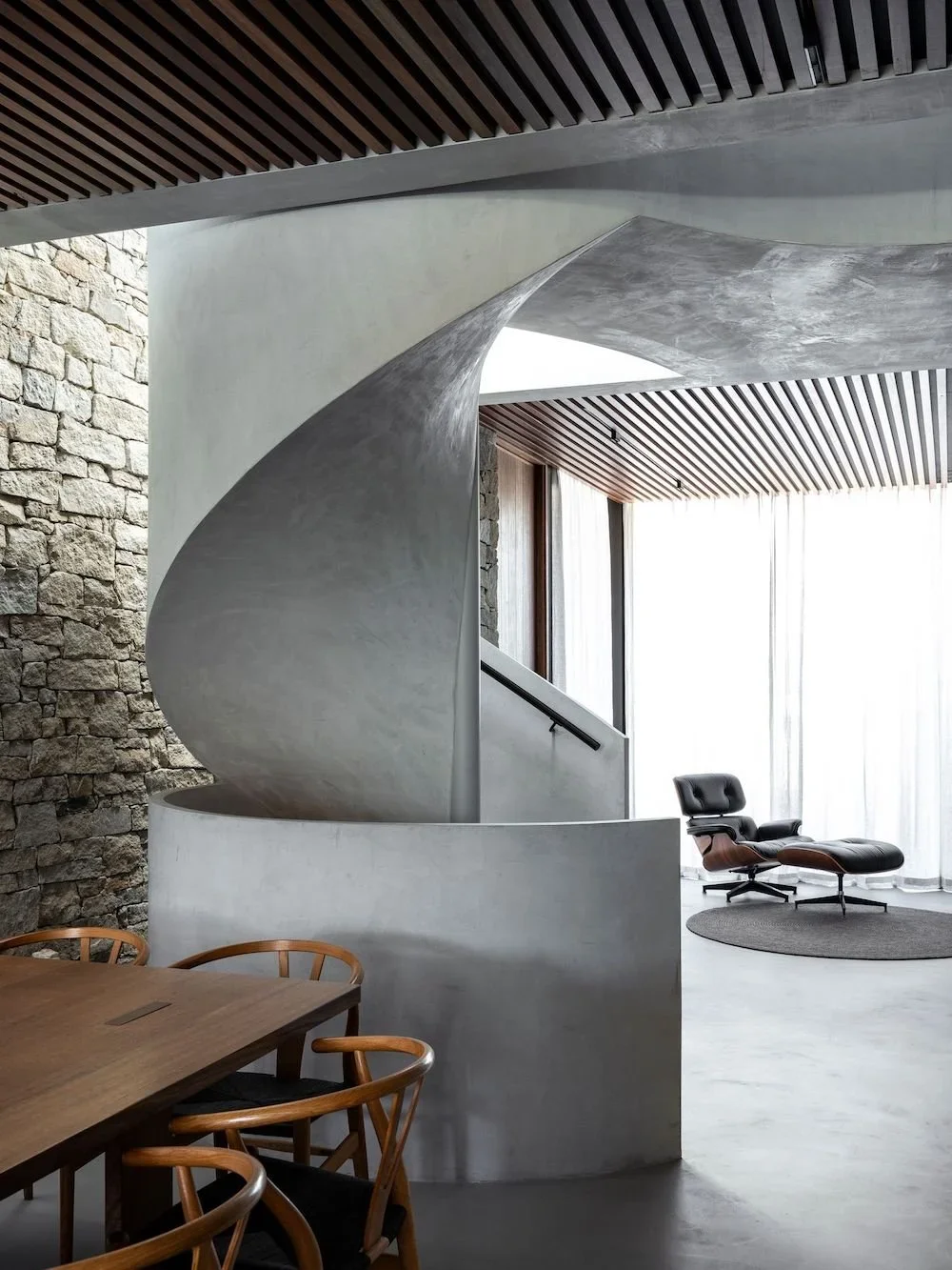 Modern interior featuring a curved microcement staircase and microcement from floor to ceiling