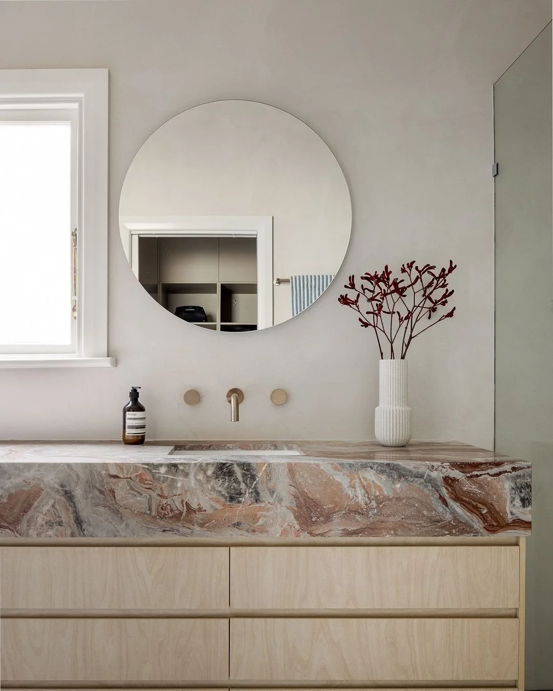 Warm beige microcement walls complement a custom marble vanity 