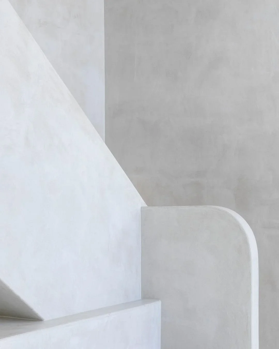 Close-up of minimalist white microcement architectural stairway with smooth curved and angular shapes