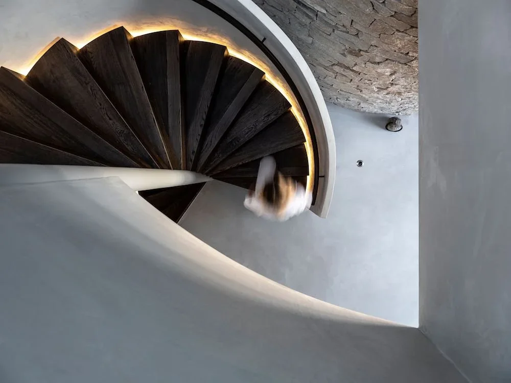 Seamless, curved microcement staircase application complemented by warm rope lighting in a coastal luxury new construction home