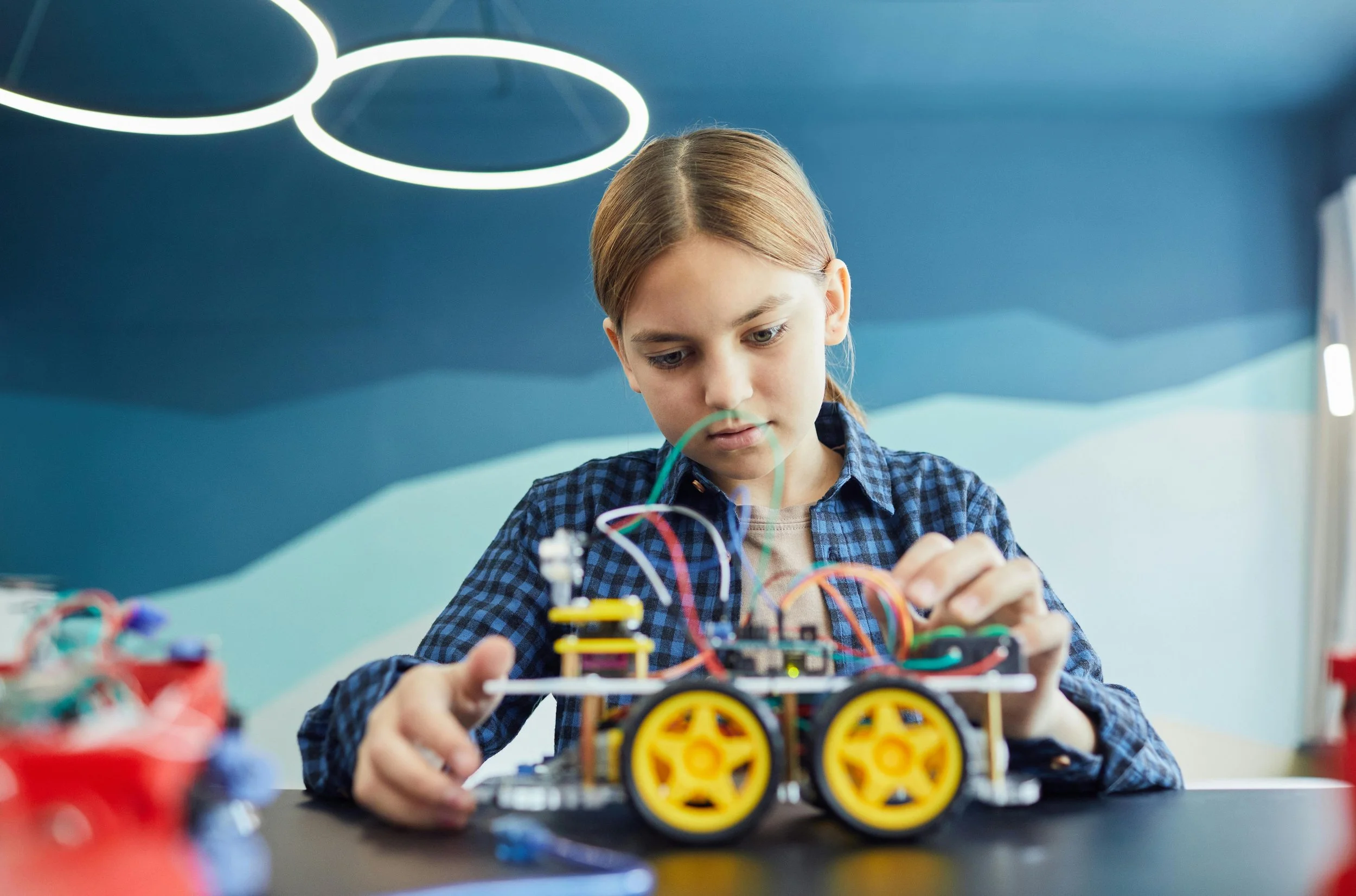 A young girl works on an engineering problem involving creating a small electrical-powered racecar. Representing the insights of Joseph Catalino on fatherhood.