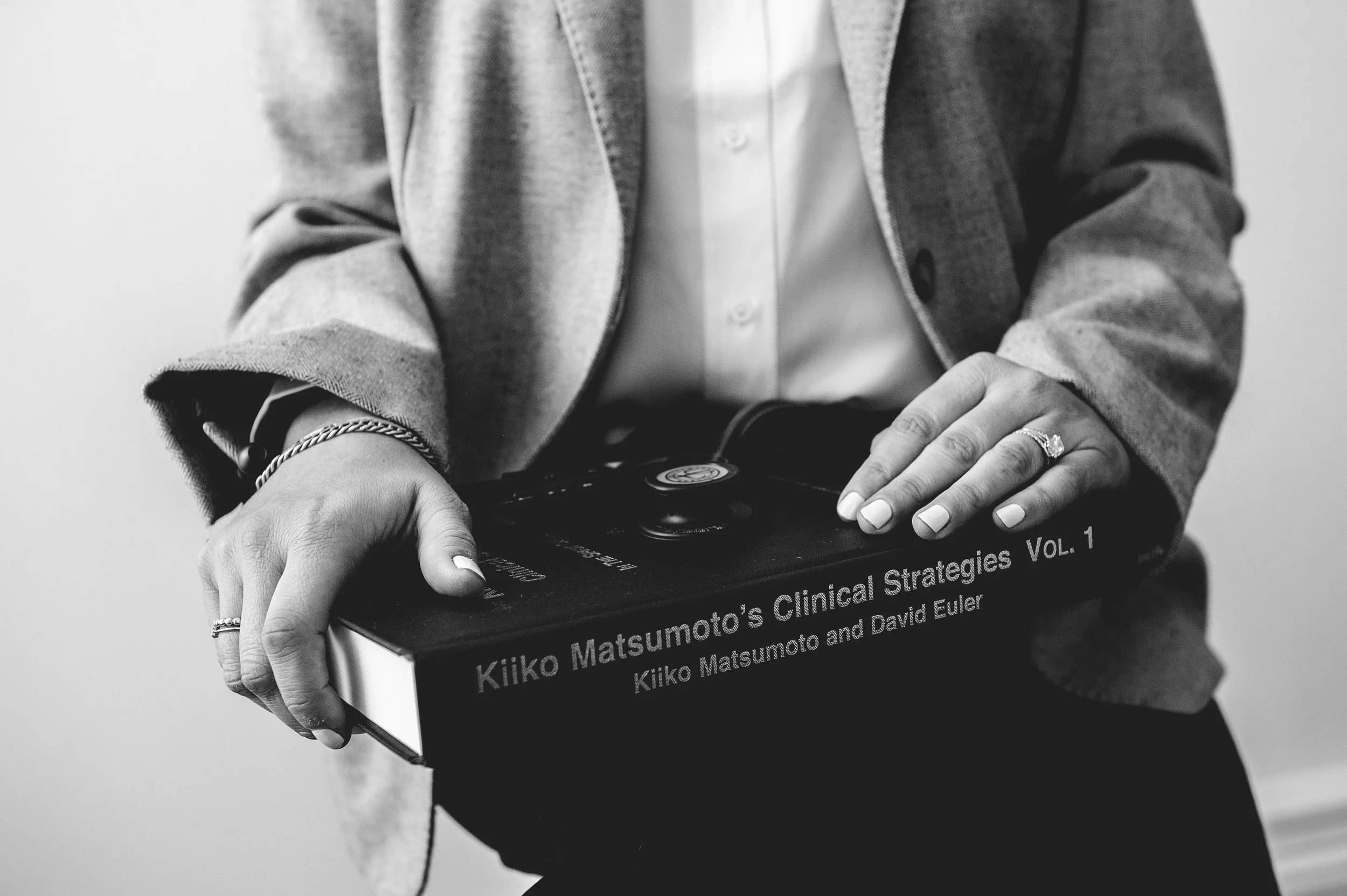 Dr. Warren holding Kiiko Matsumoto textbook in lap, black and white