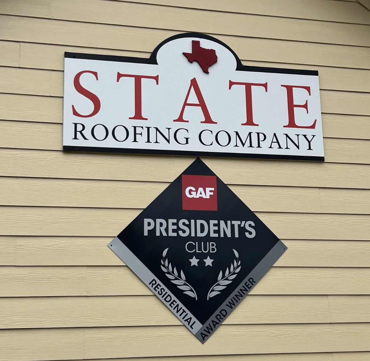 Sign for State Roofing Company with a red Texas shape and roof graphic, also displaying GAF President's Club award