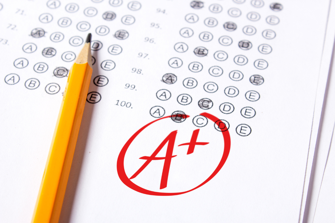 Multiple-choice test answer sheet with marked answers, a yellow pencil, and a red A+ grade