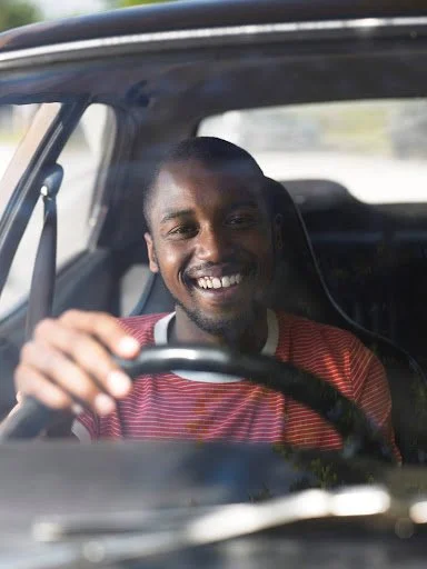 A man smiling while driving a car.