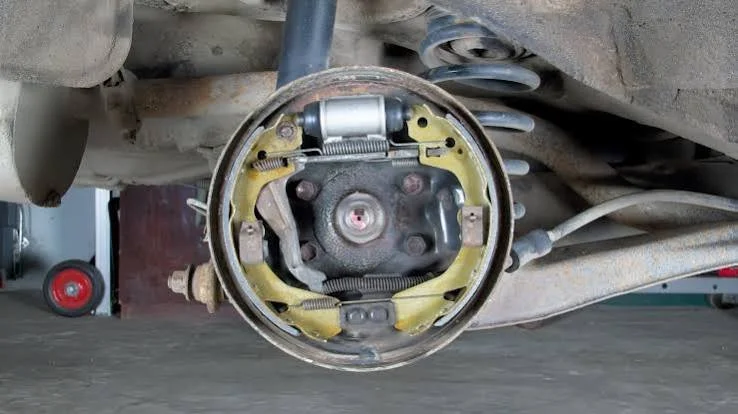 Close-up of a disassembled drum brake assembly on a vehicle's wheel hub, showing springs and brake shoes.