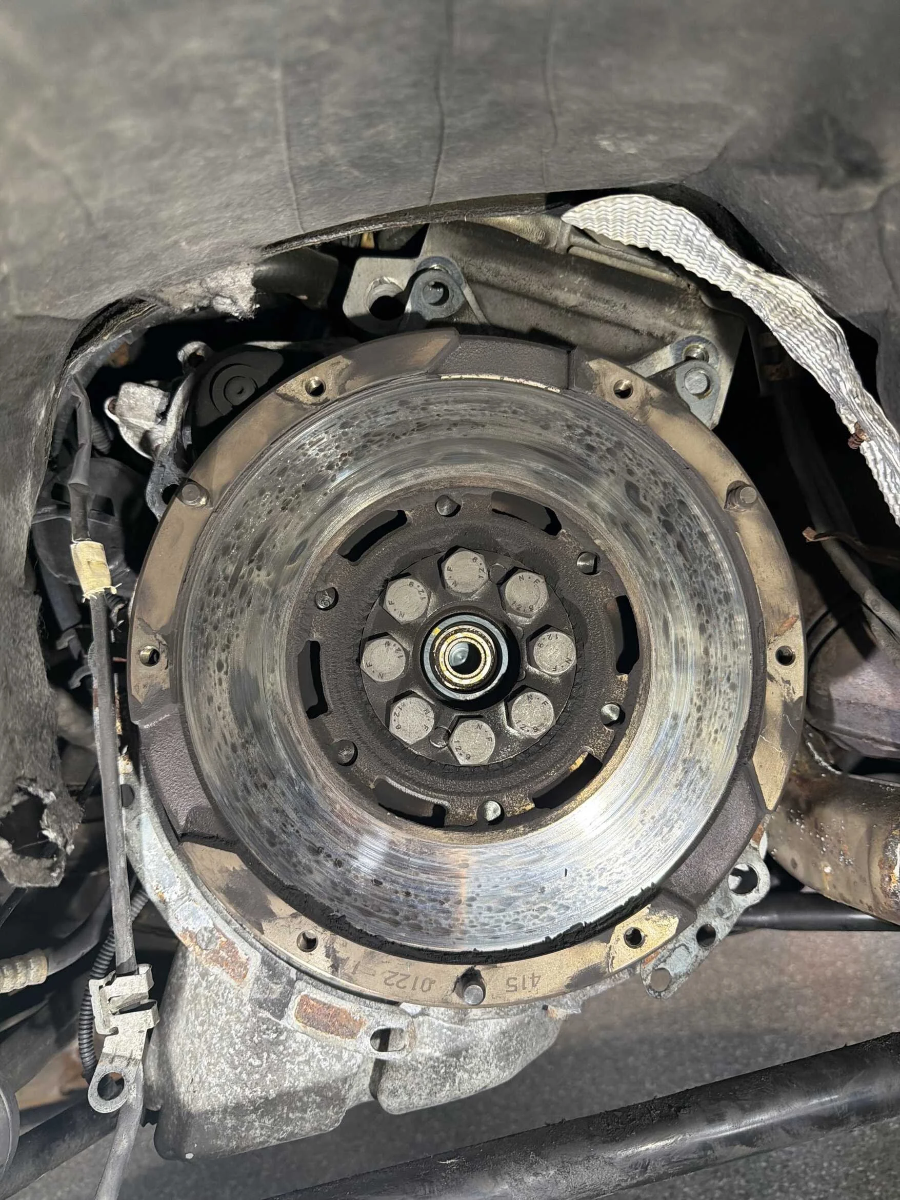 Close-up of a disassembled car engine component, revealing the engine's internal metal parts and bolt holes.