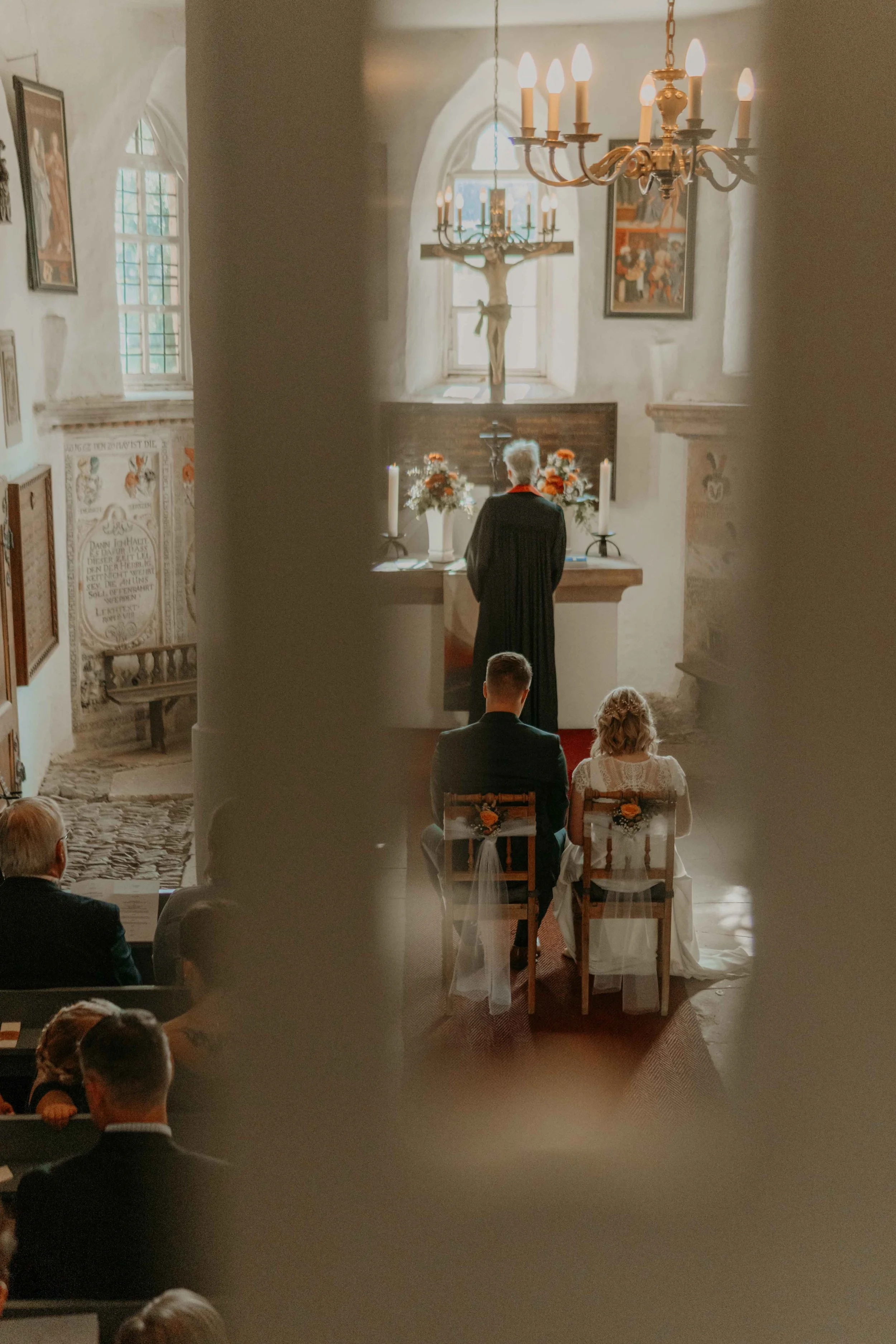 Trauung in der Kirche in Hessen, Brautpaar sitzt vor dem Altar, Foto von hinten.