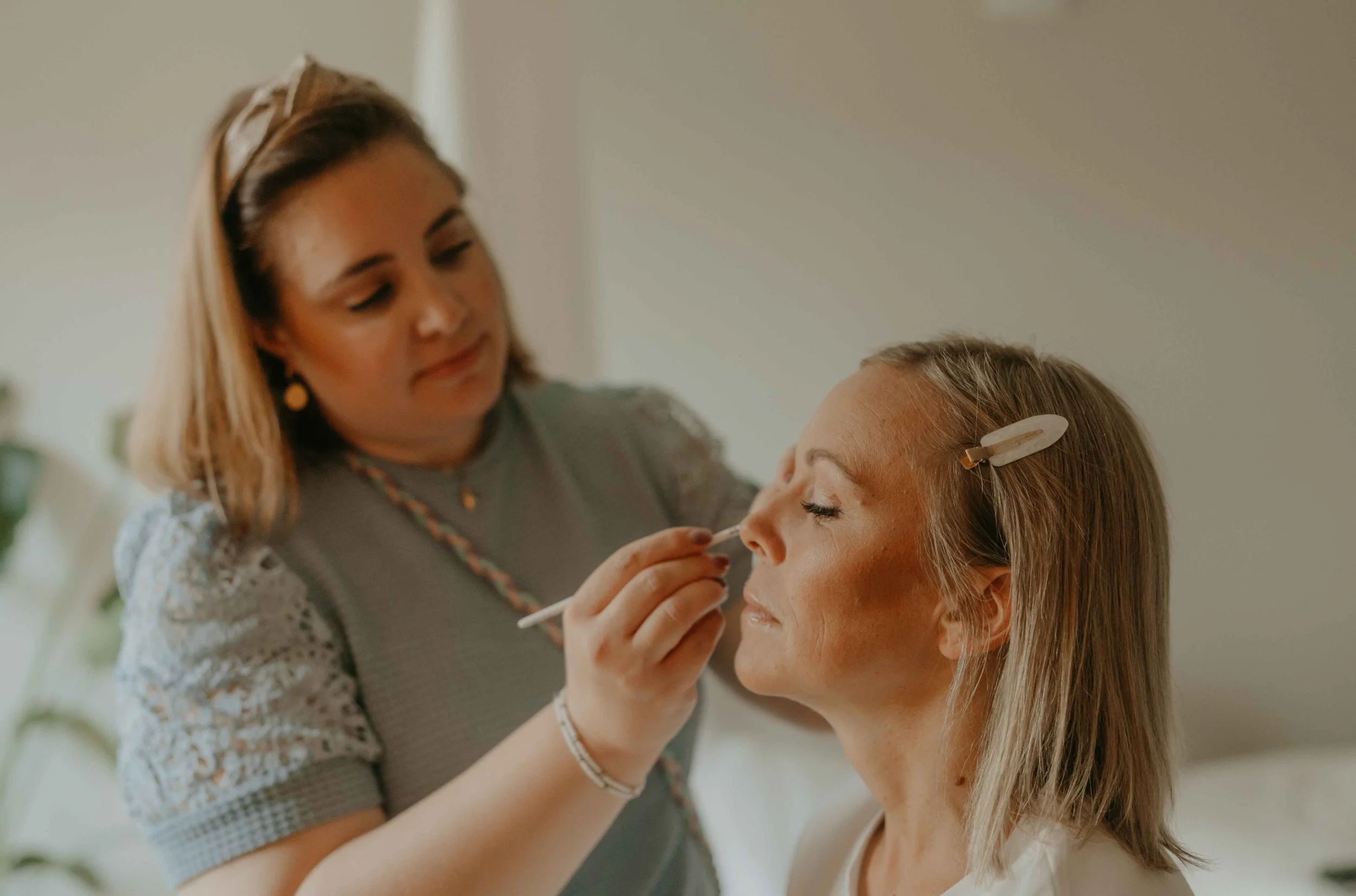 Braut wird von Stylistin in der Hof Suite geschminkt und gestylt, Getting Ready Moment voller Vorfreude und Präzision. 