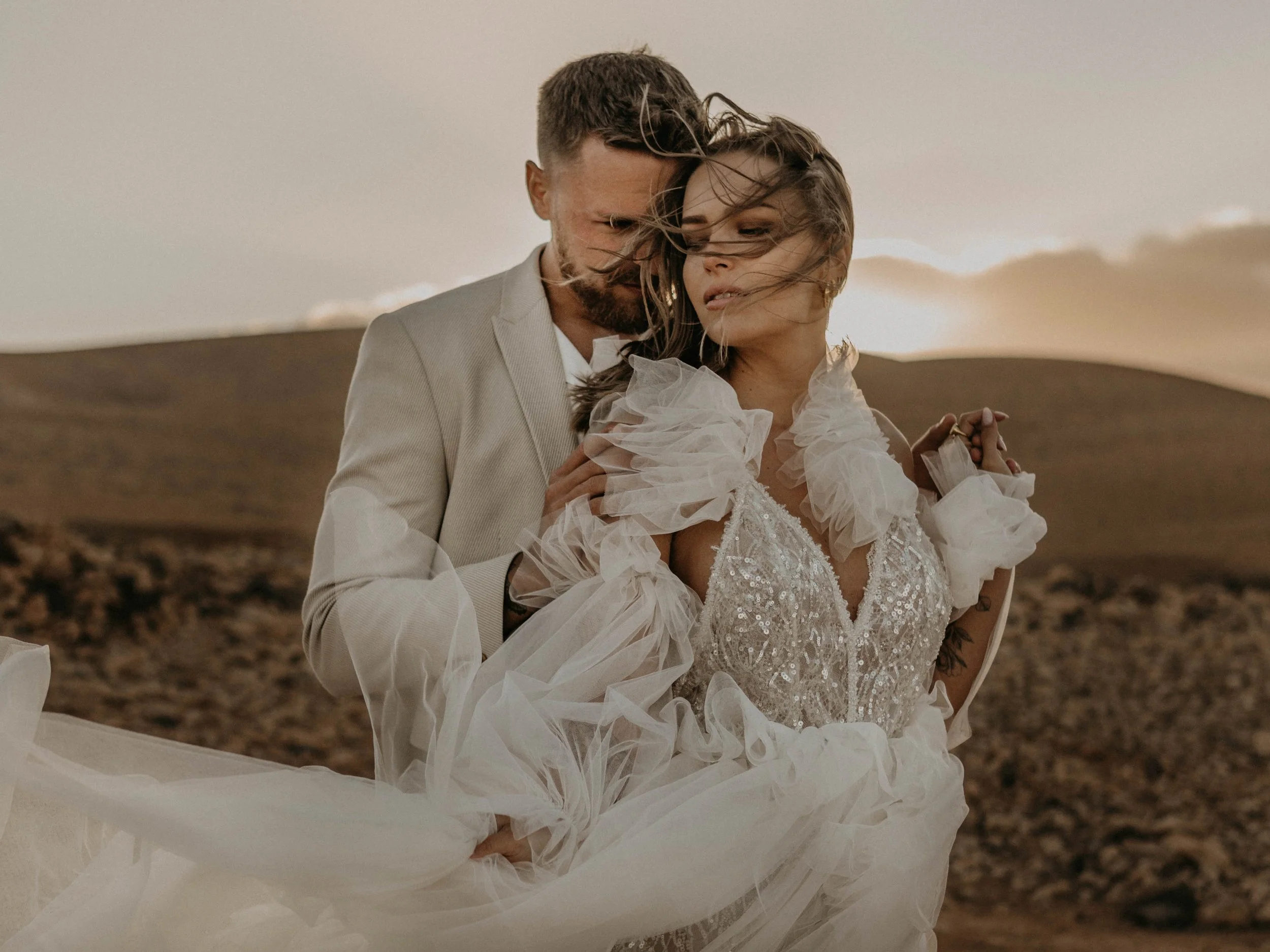 Intimate Destination Wedding Spain, Fuerteventura – Brautpaar in einer warmen, leidenschaftlichen Umarmung in den weiten Fuerteventuras bei magischem Sonnenuntergang.