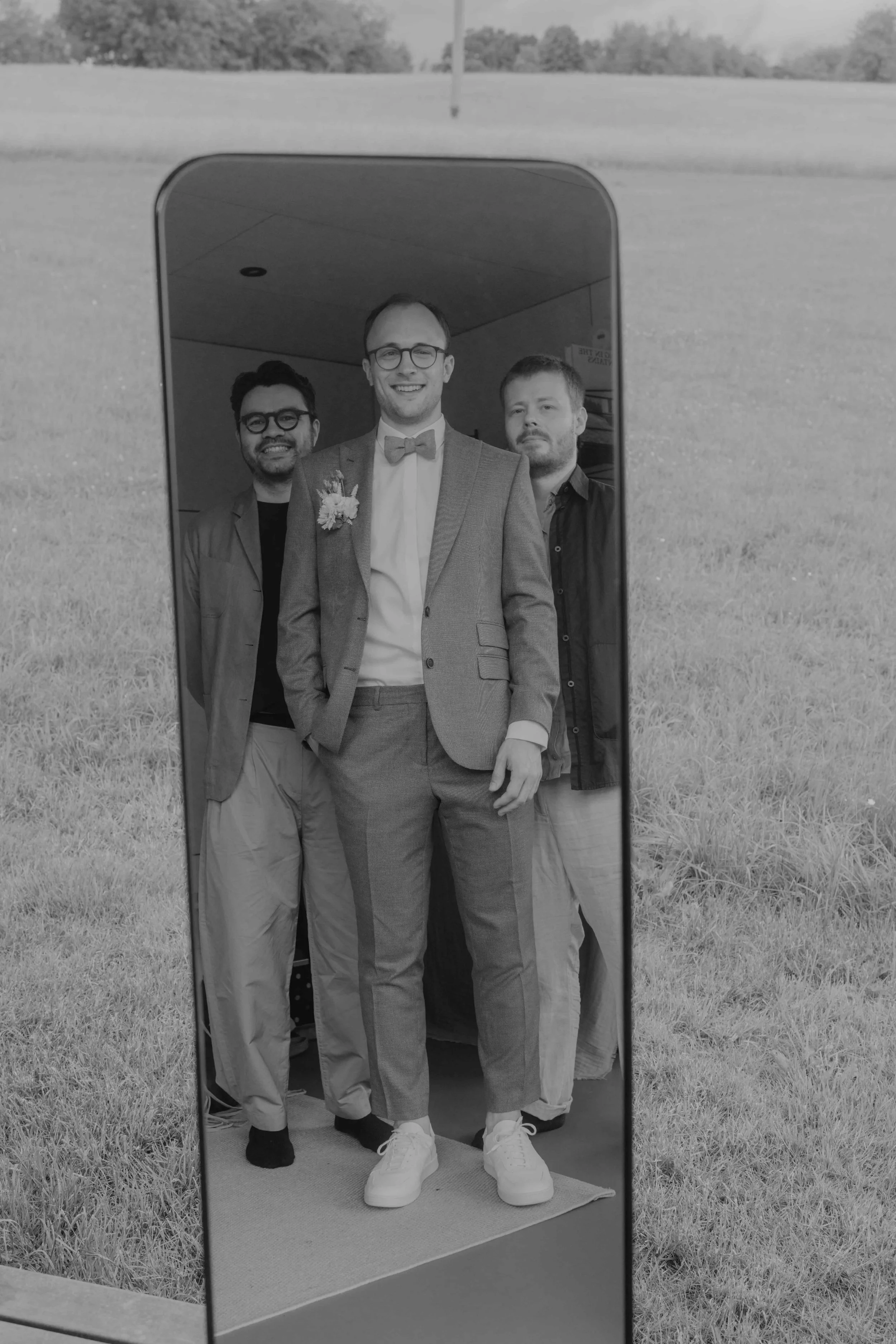 Bräutigam und seine zwei besten Freunde lachen beim Anziehen der Sakkos.