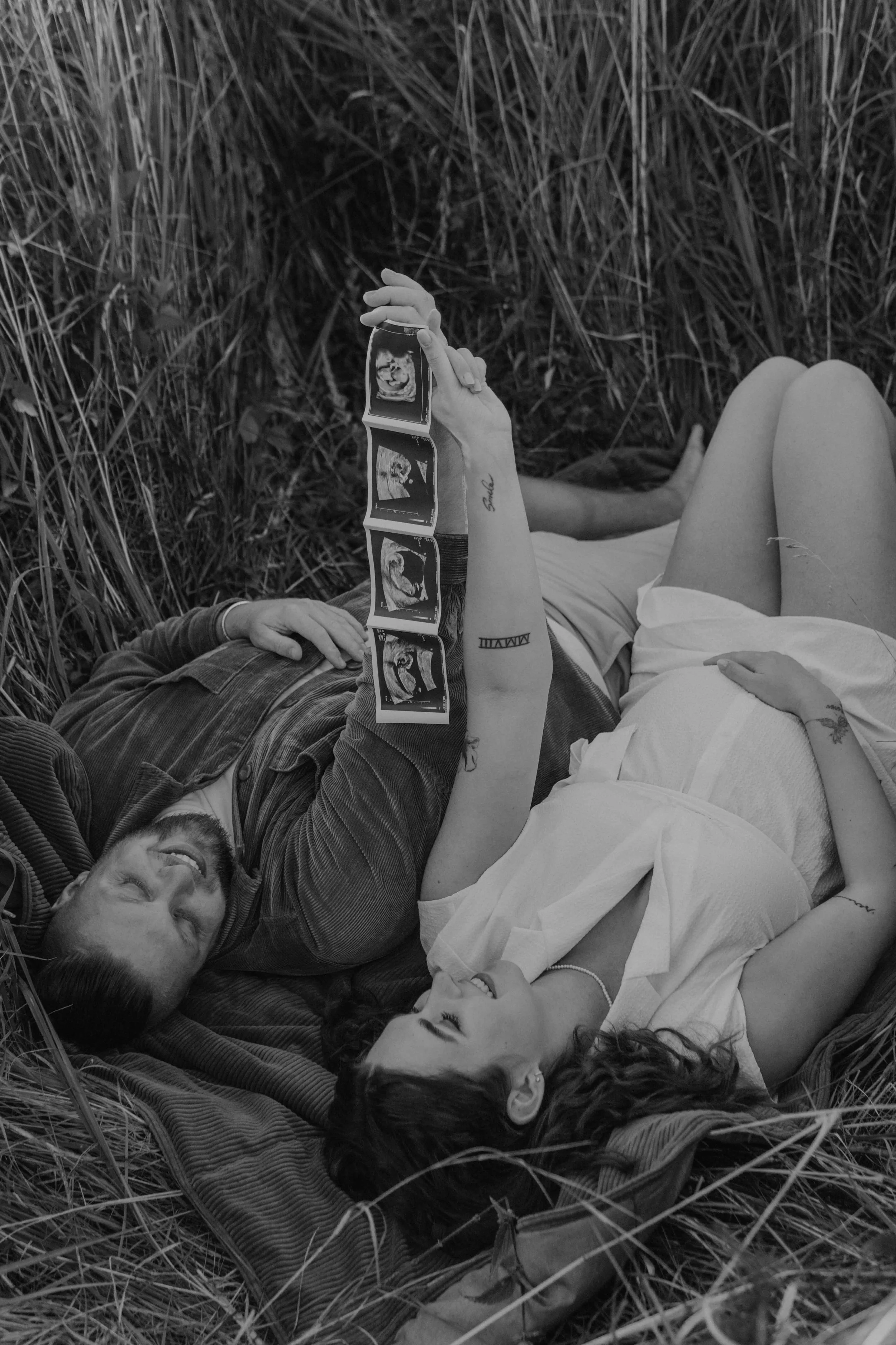 Babybauchshooting Hamburg – werdende Elternhalten Ultraschallbild hoch im Sonnenuntergang.