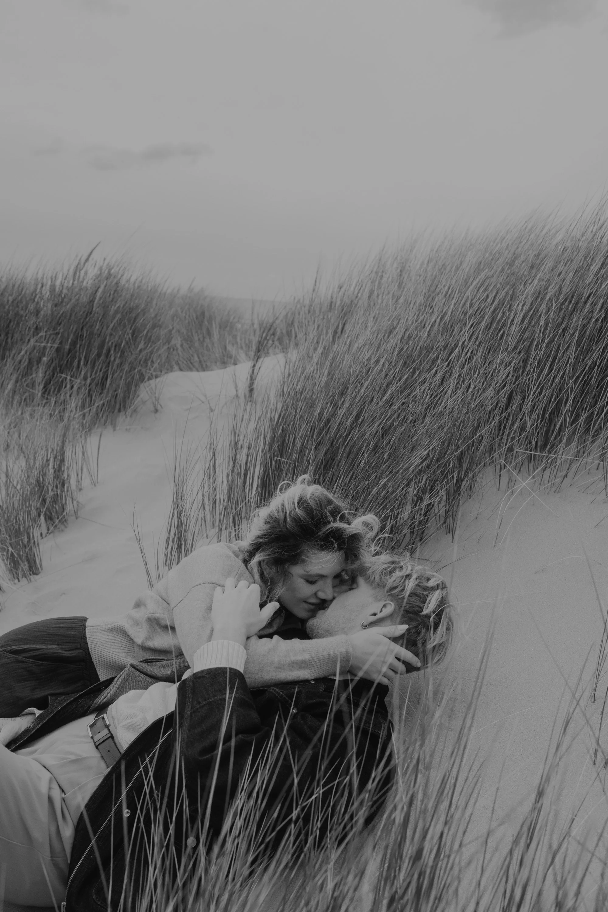 Paarshooting Holland – inniger Moment im Dünengras bei Sturm an der Küste.