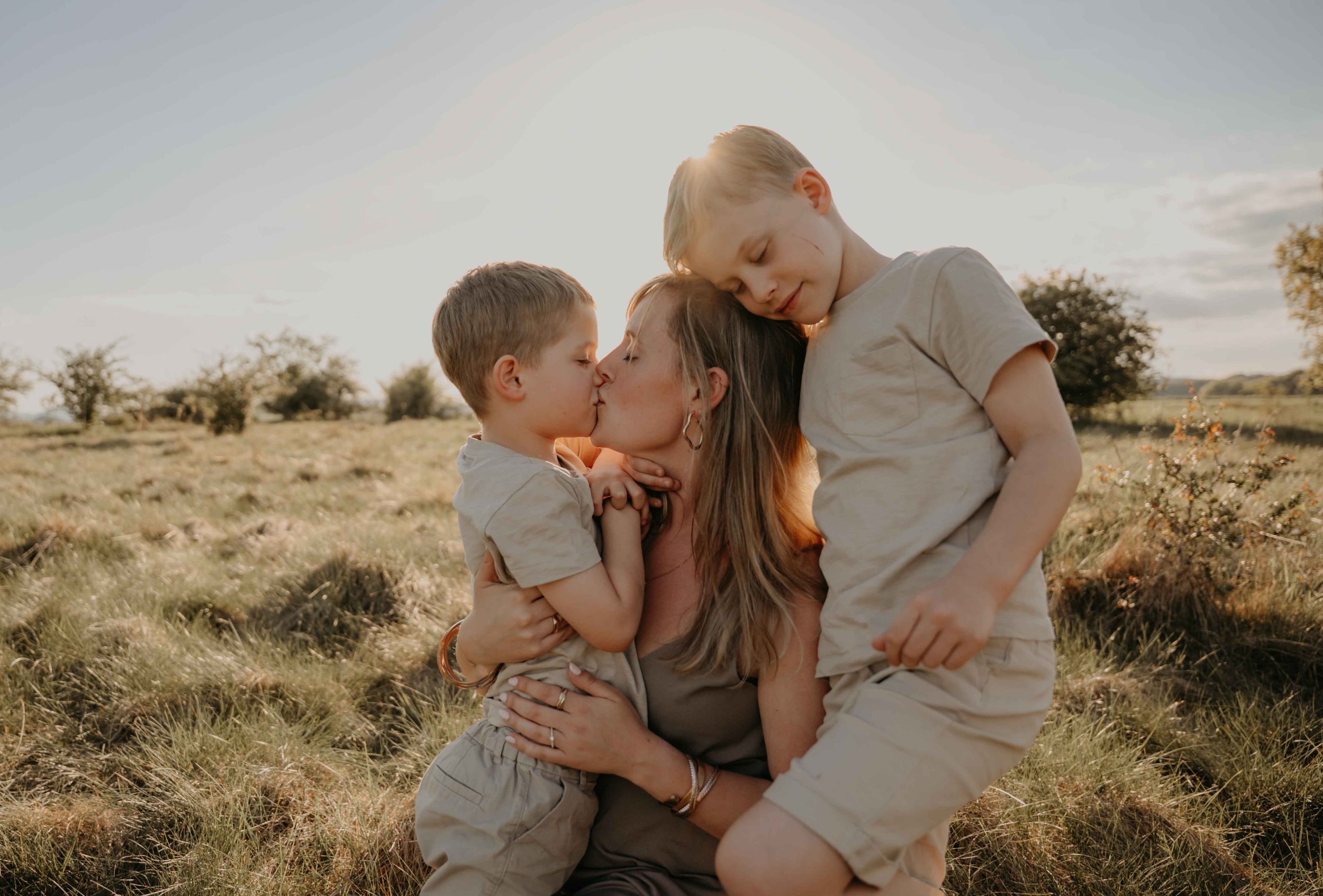 Familienfotografie Nordhessen – Mutter hält ihre Kinder im Arm, Innige Umarmung und Küsschen.