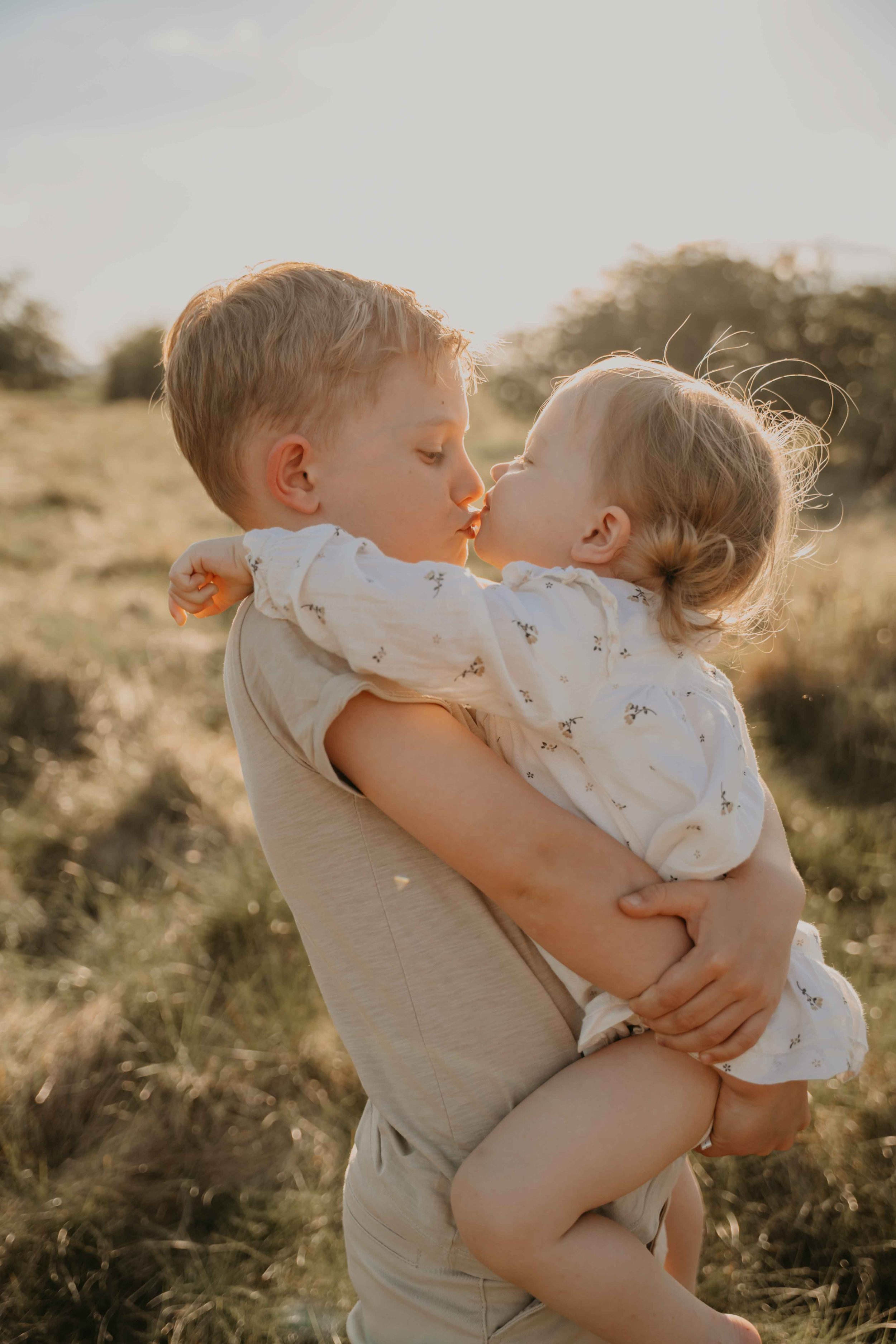 Familienfotografie Kassel –Geschwister geben sich ein Küsschen.