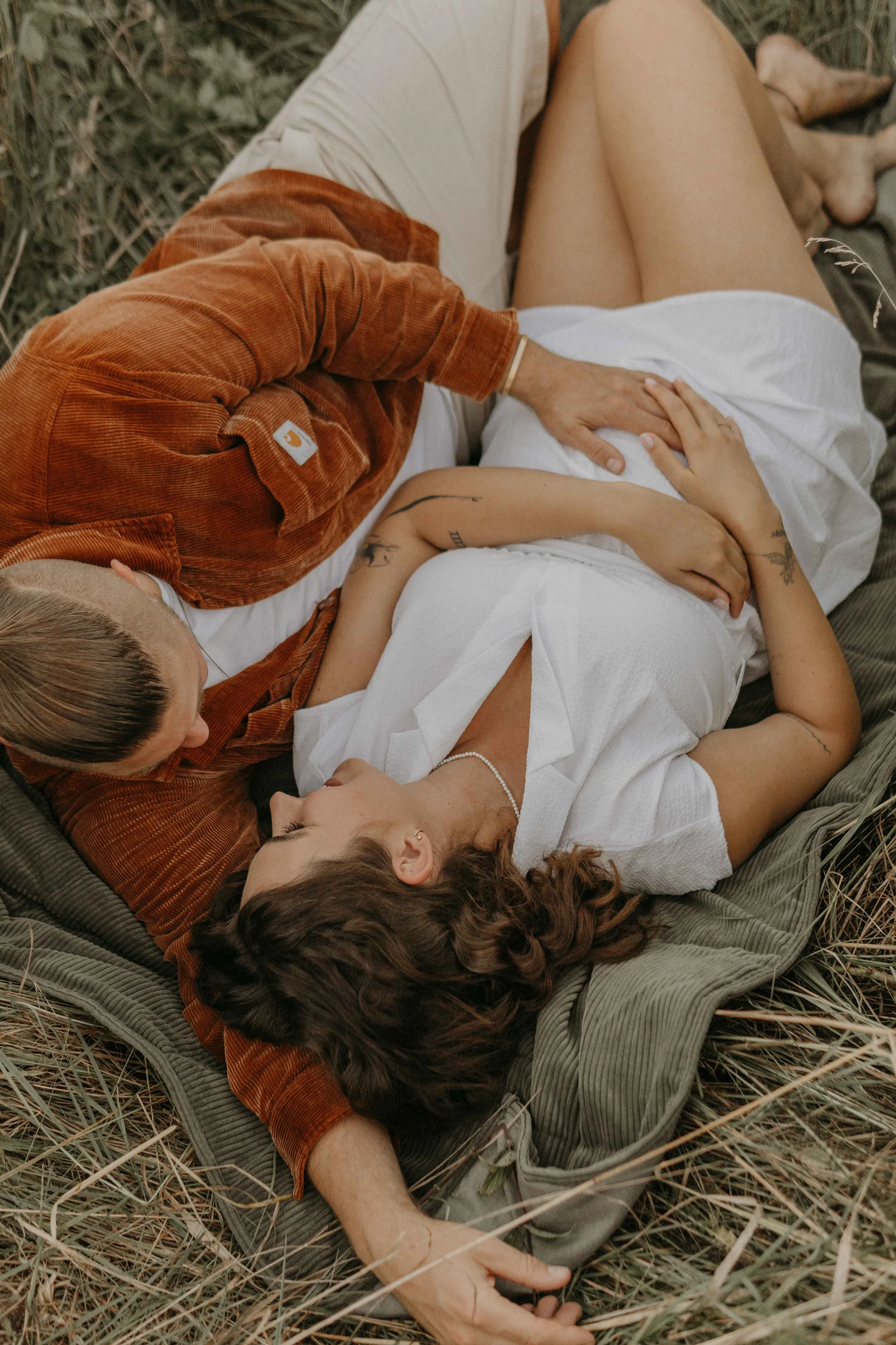 Babybauchshooting Hamburg – werdende Eltern hält zärtlich den BabyBauch und das Ultraschallbild im Sonnenuntergang.