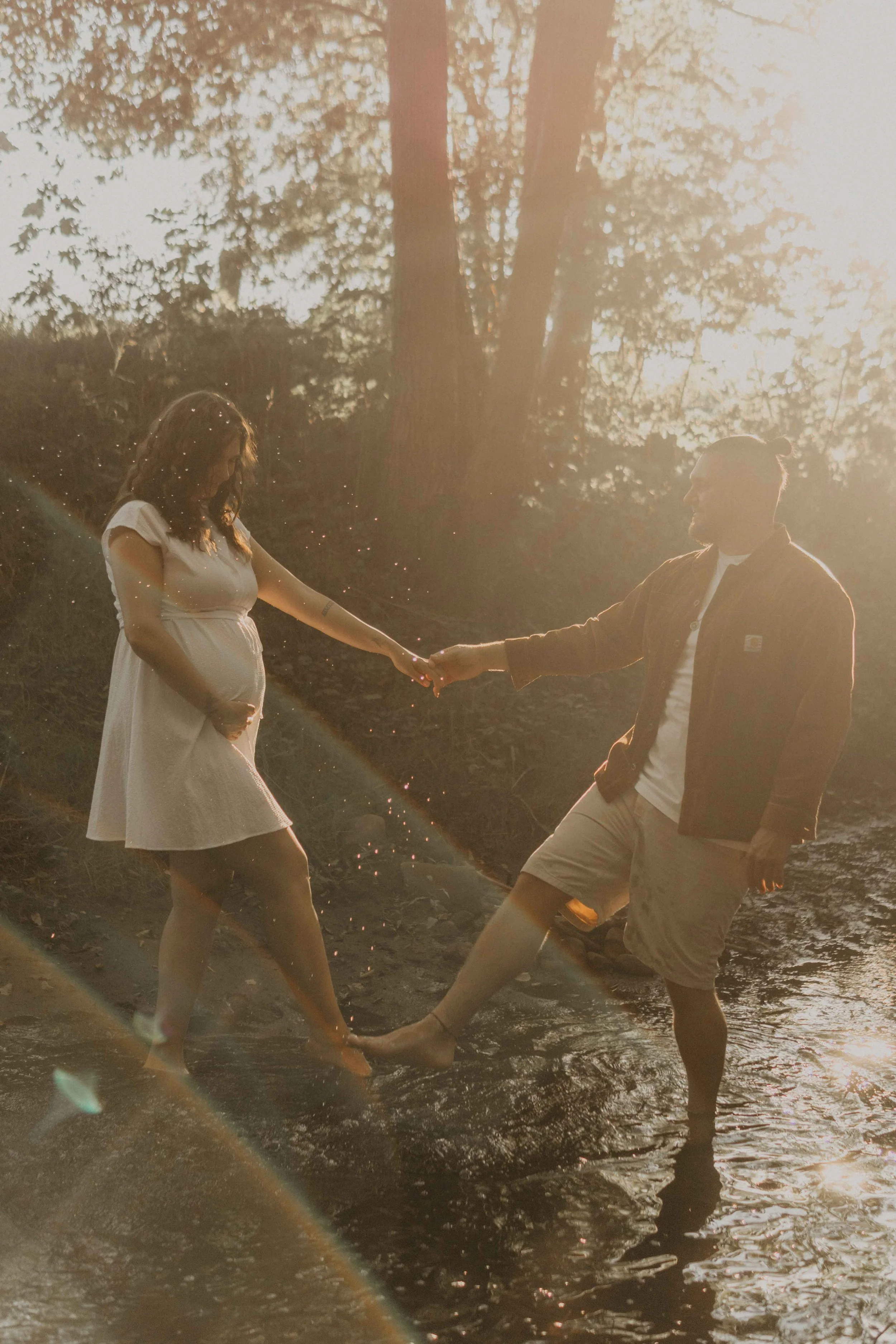 Maternety Shooting Hamburg – werdende Eltern toben im Bach mit dem Wasser und genießen den Sonnenuntergang.