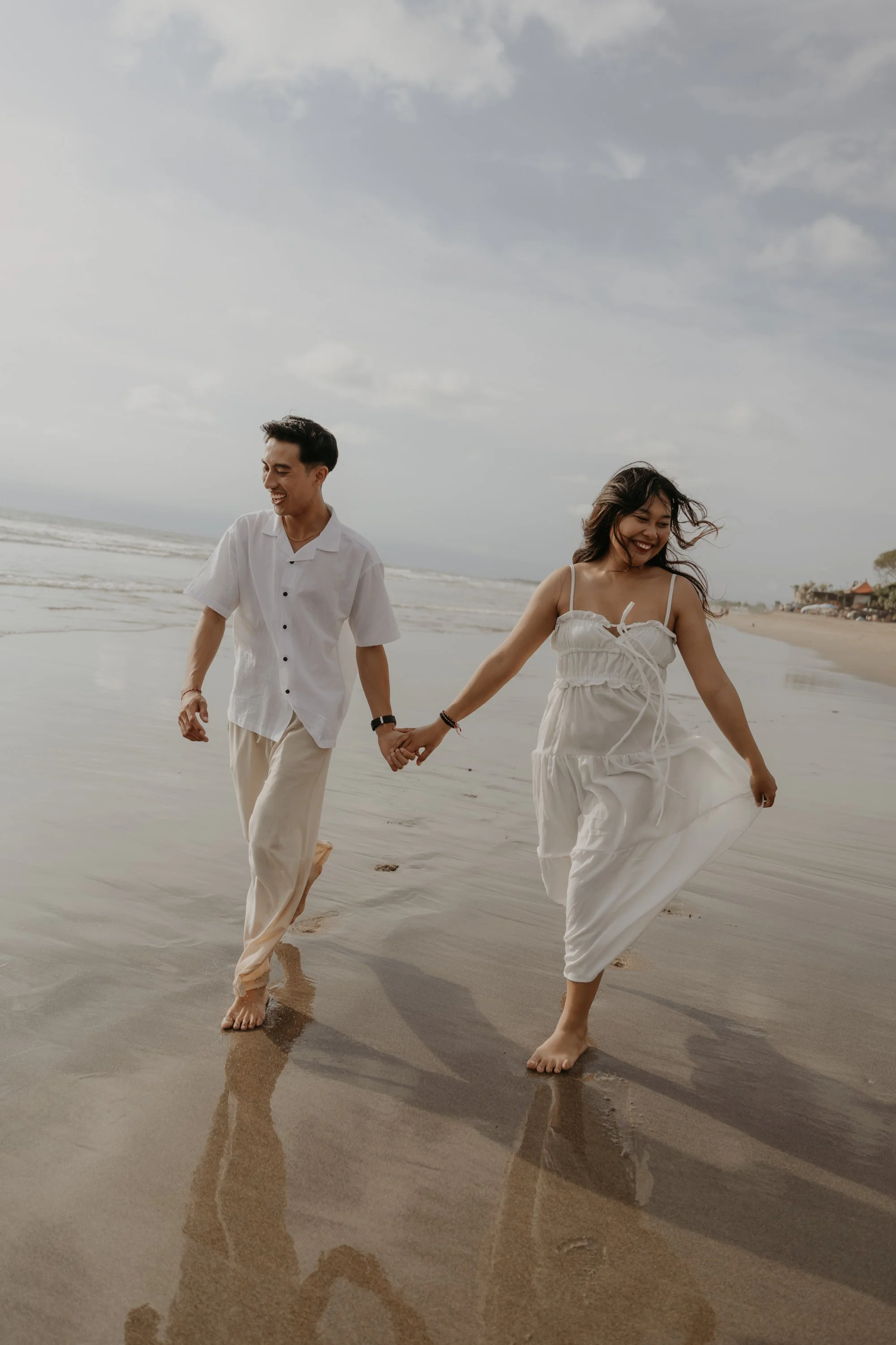 Destination Wedding Bali – Brautpaar barfuß am Strand bei Sonnenuntergang.