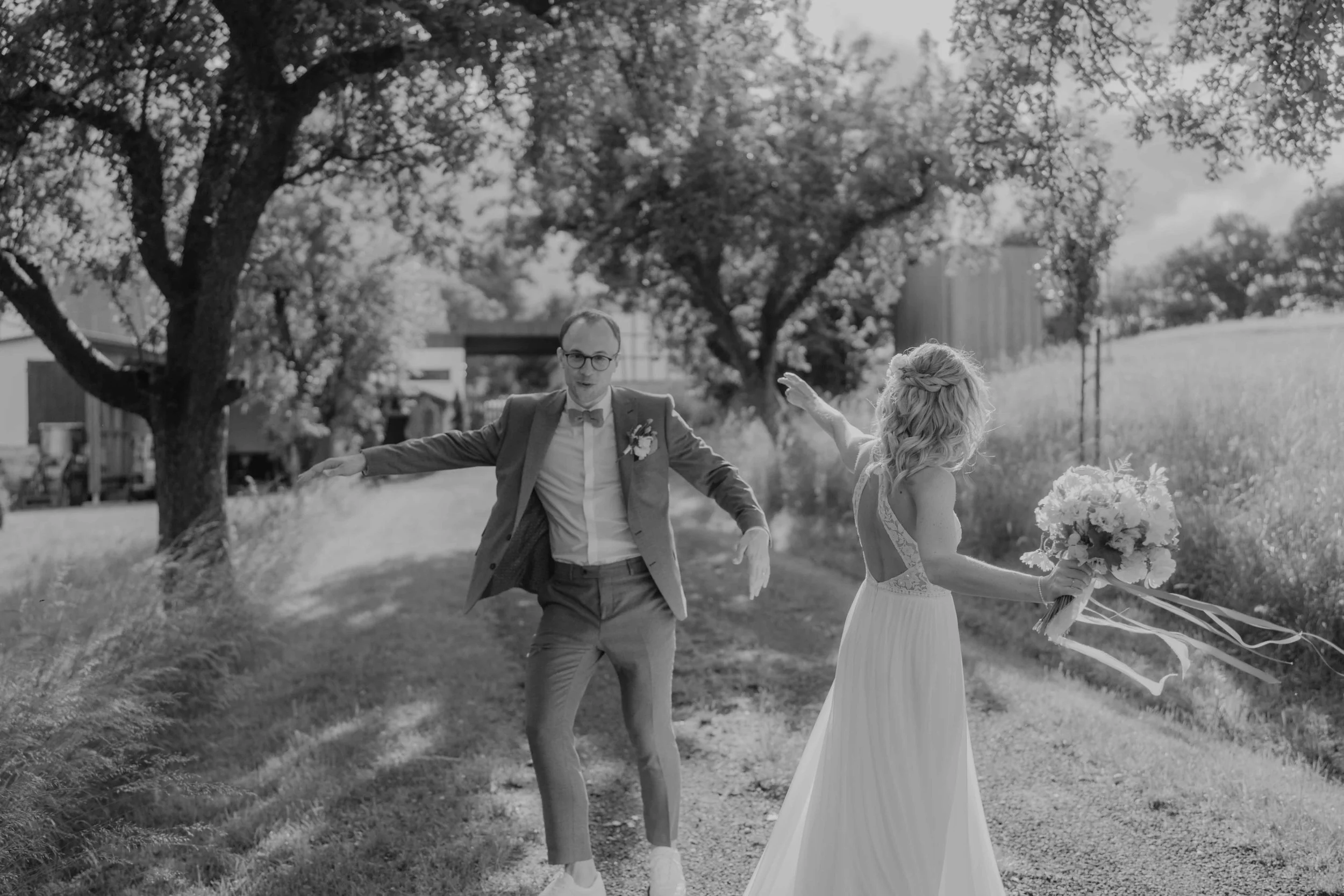 Dokumentarische Hochzeitsfotografie Deutschland – Paar tanzt euphorisch über eine Wiese in Nordhessen.