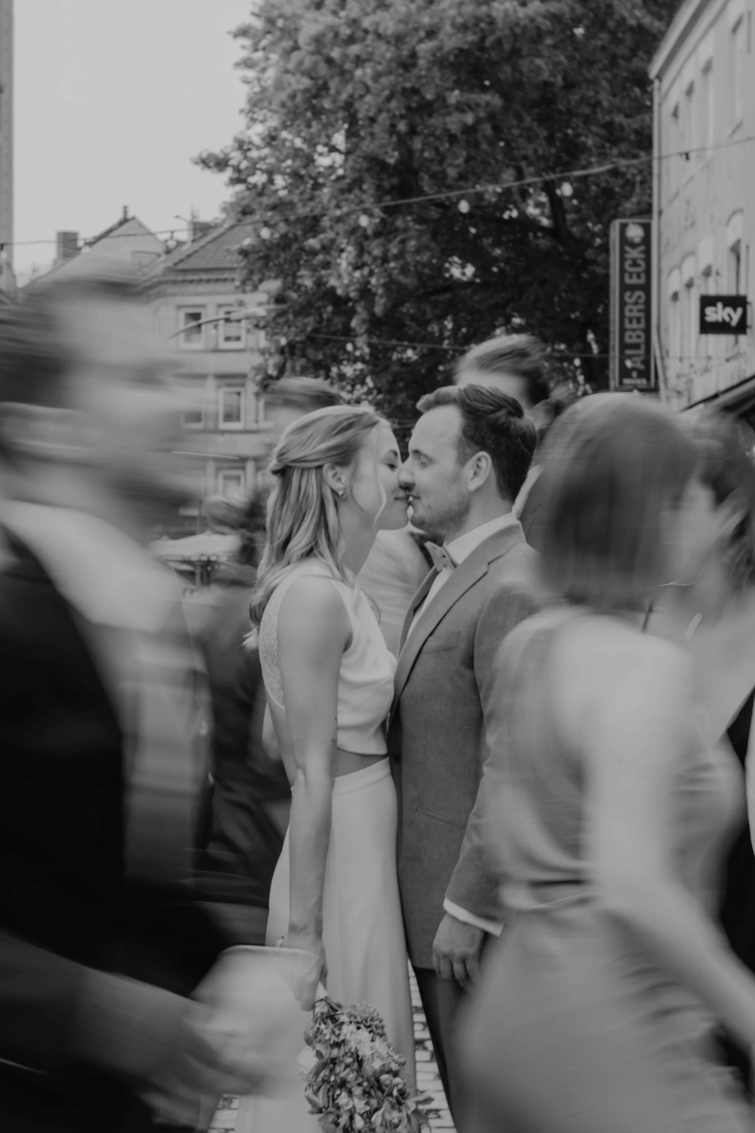 Editorial Hochzeit Hamburg Kiez – Brautpaar steht in der Mitte der Reeperbahn, Gäste verschwimmen in Bewegung um sie herum, moderne und künstlerische Hochzeitsfotografie.