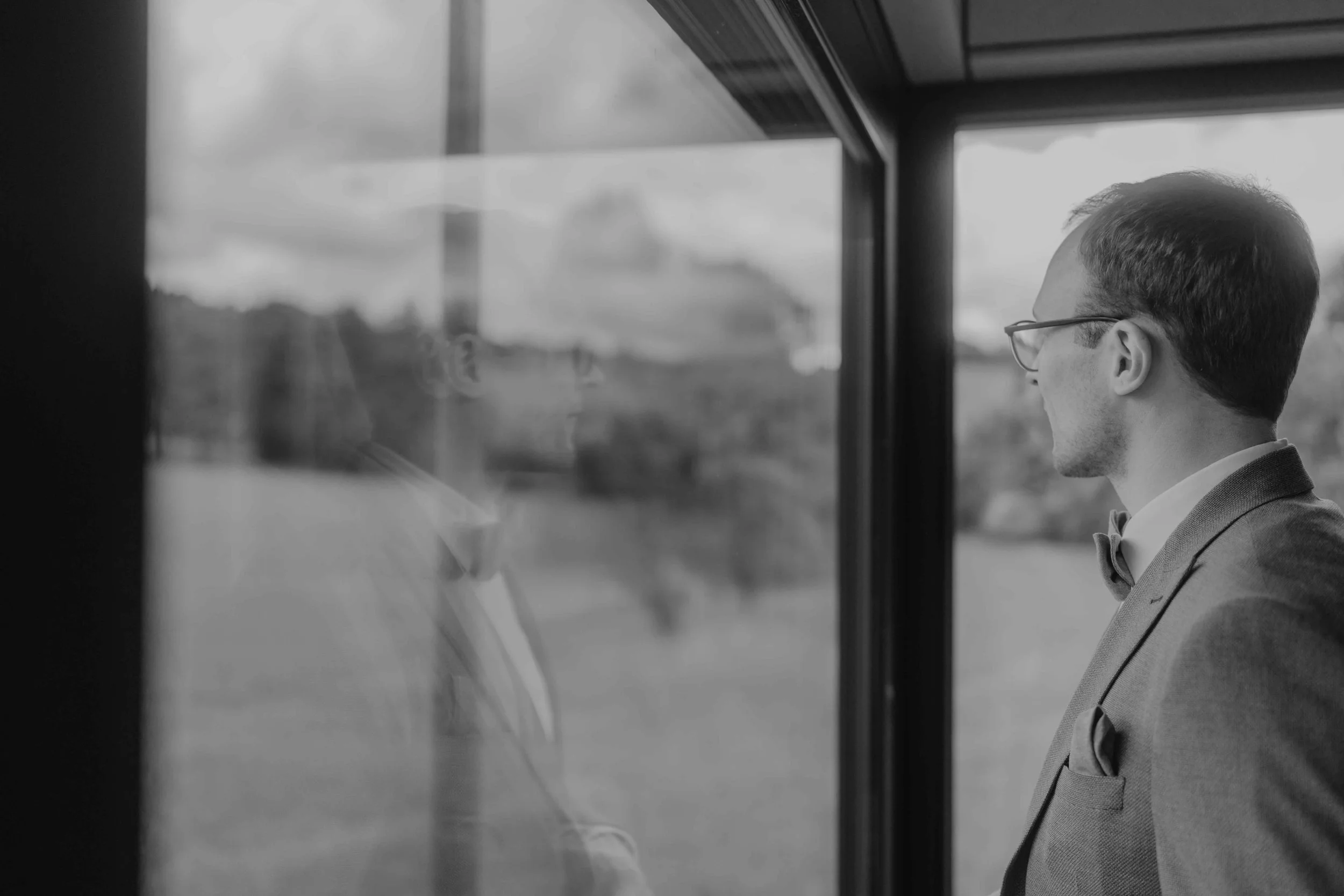 Bräutigam blickt aus dem Fenster des Tiny House, nachdenklicher Moment.