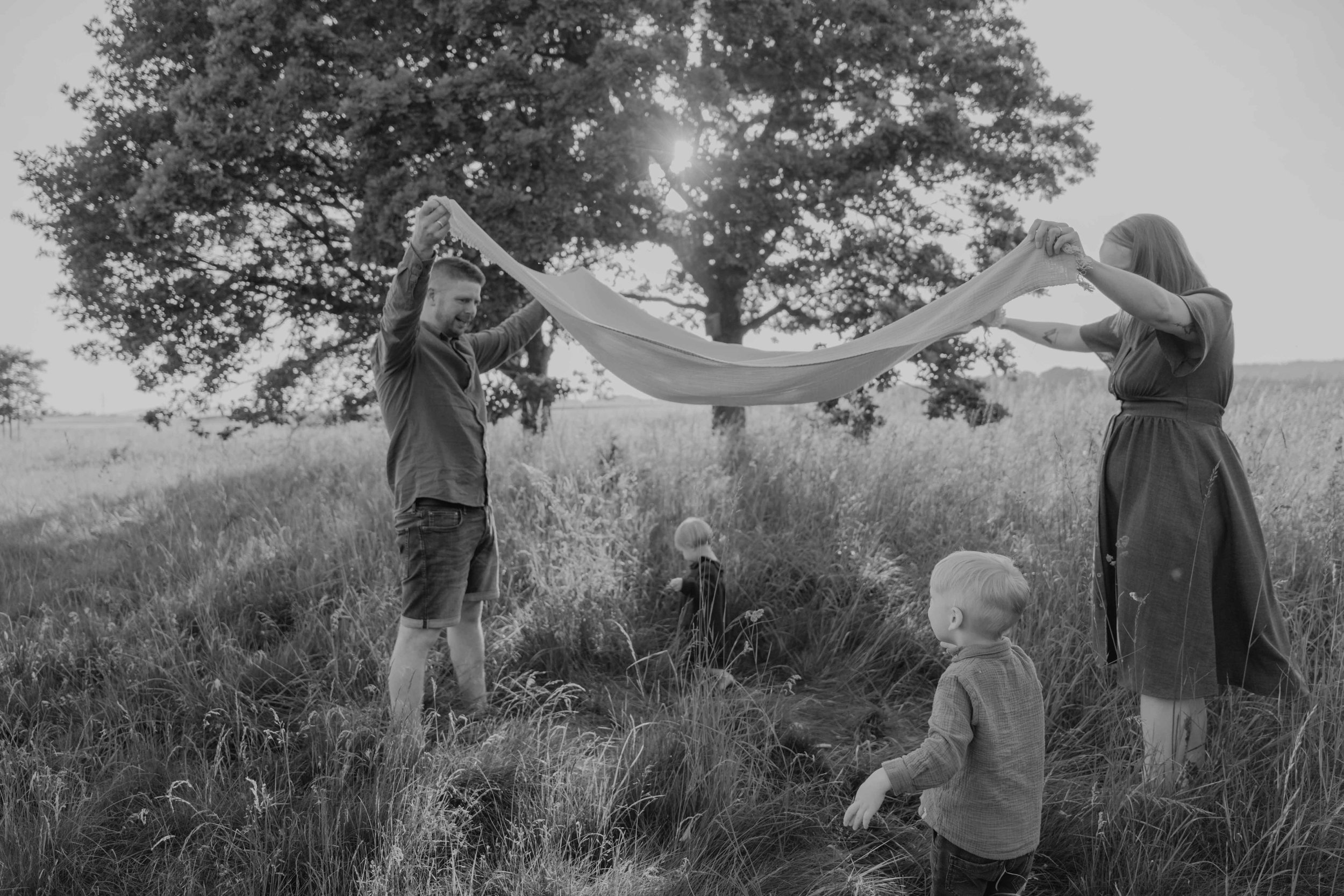 Familienshooting draußen – Kinder laufen barfuß über eine Wiese, ungestellt und frei.