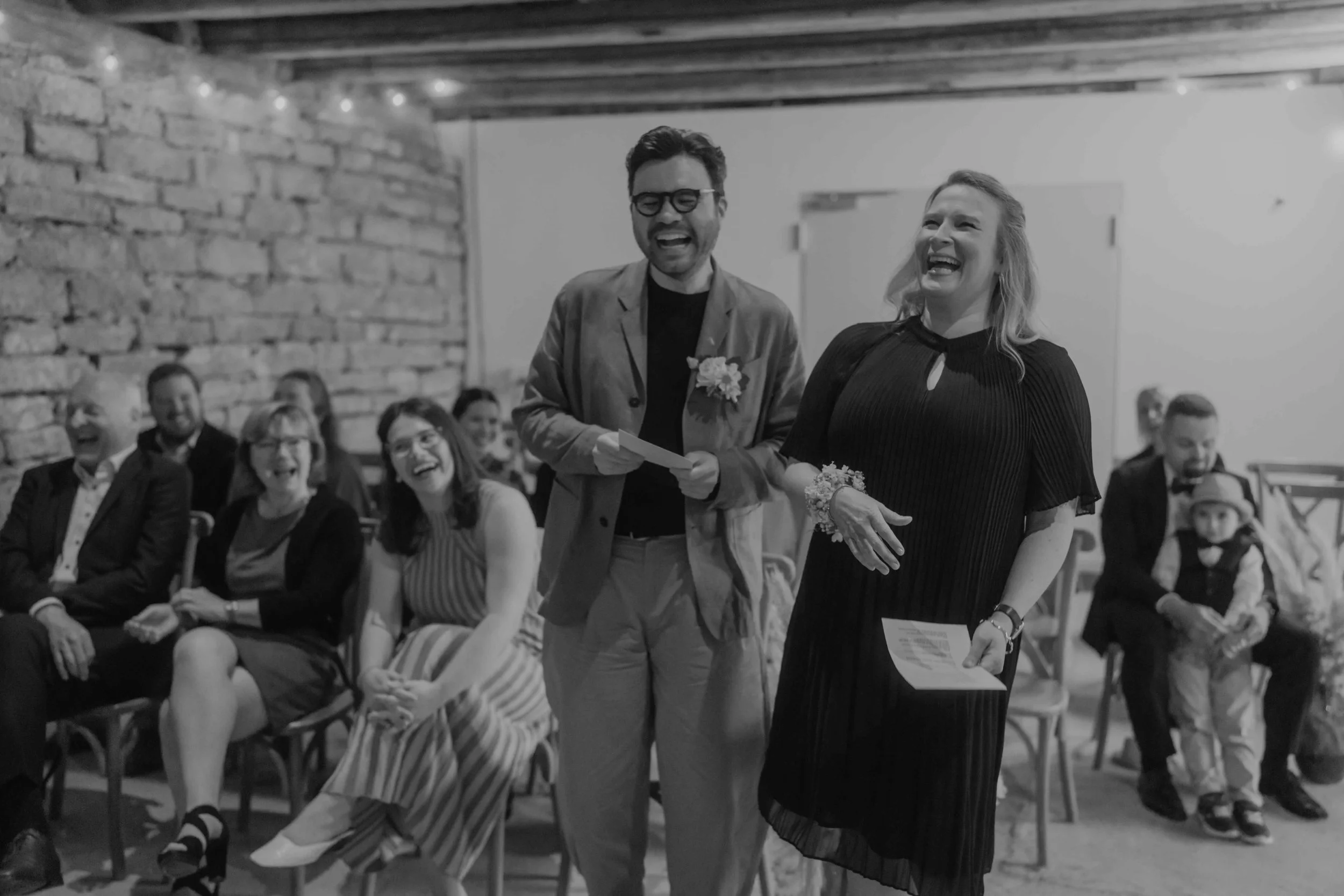 Hochzeitsfotografie Hessen – Gäste verfolgen die Traurede in einer gemütlichen Hochzeitslocation auf Hof Reith. 