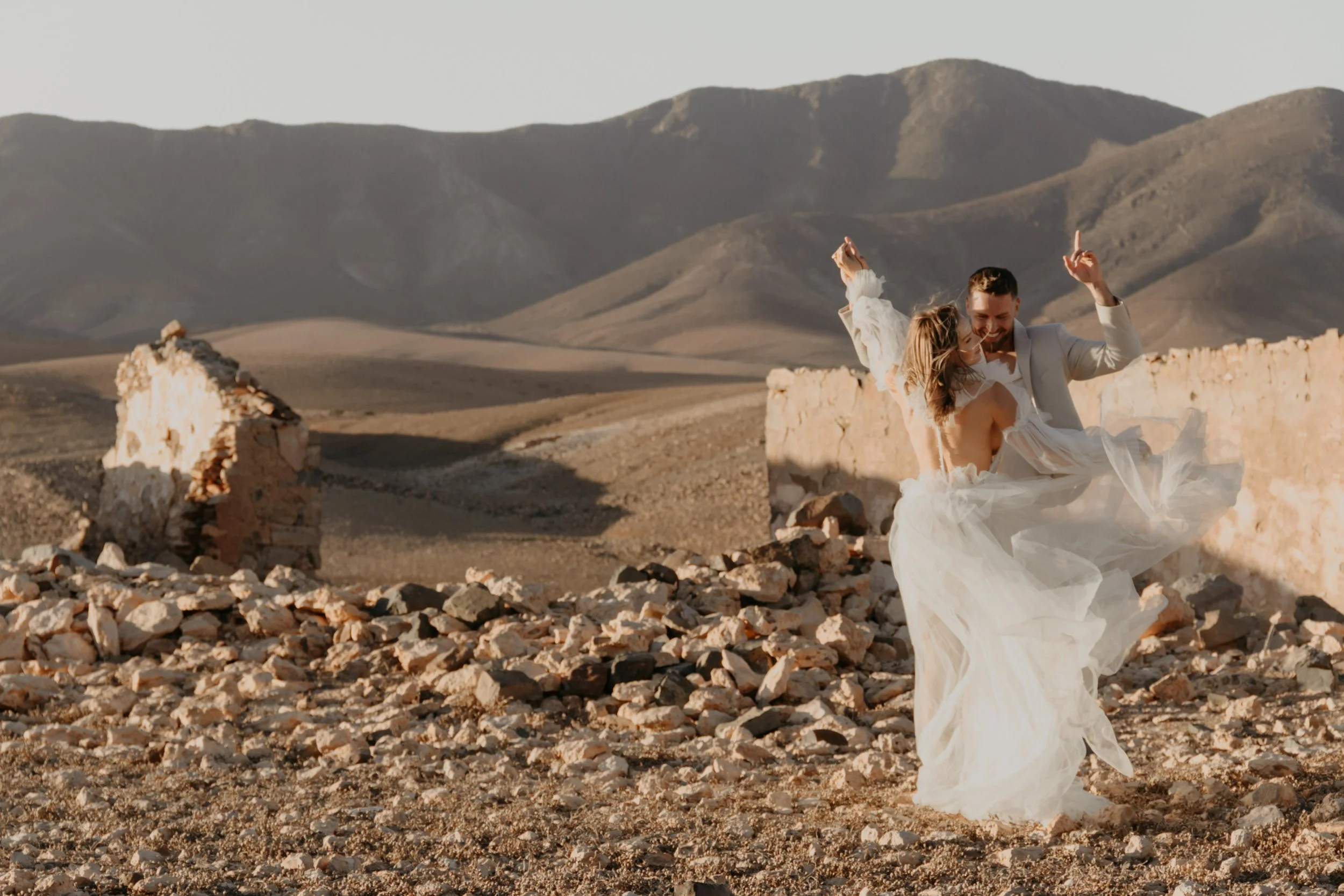 Hochzeit im Ausland – Paar tanzt barfuß in den Vulkangestein von Fuerteventura. 