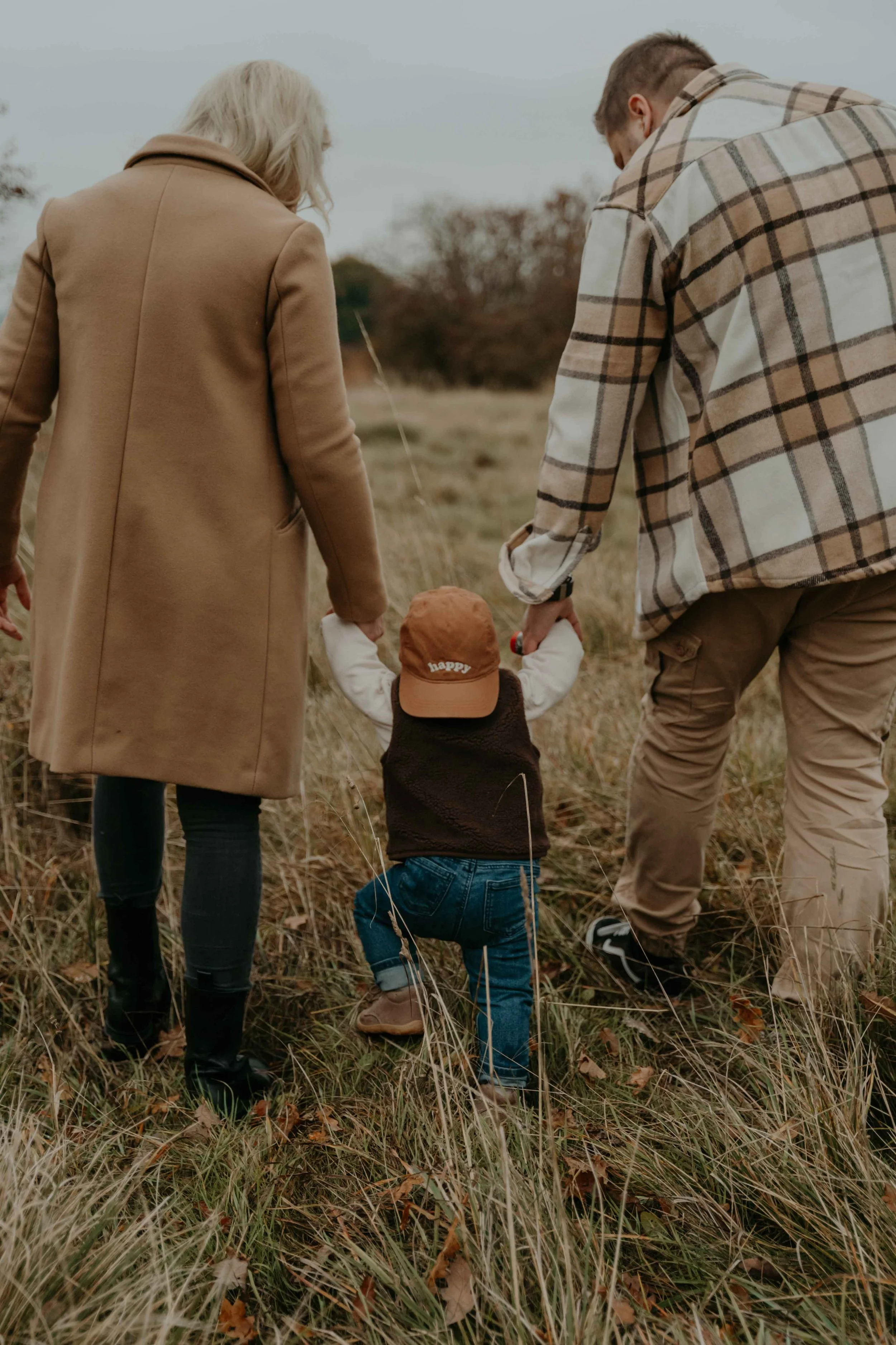 Familienshooting bei Sonnenuntergang – Familie läuft gemeinsam durch das Feld.