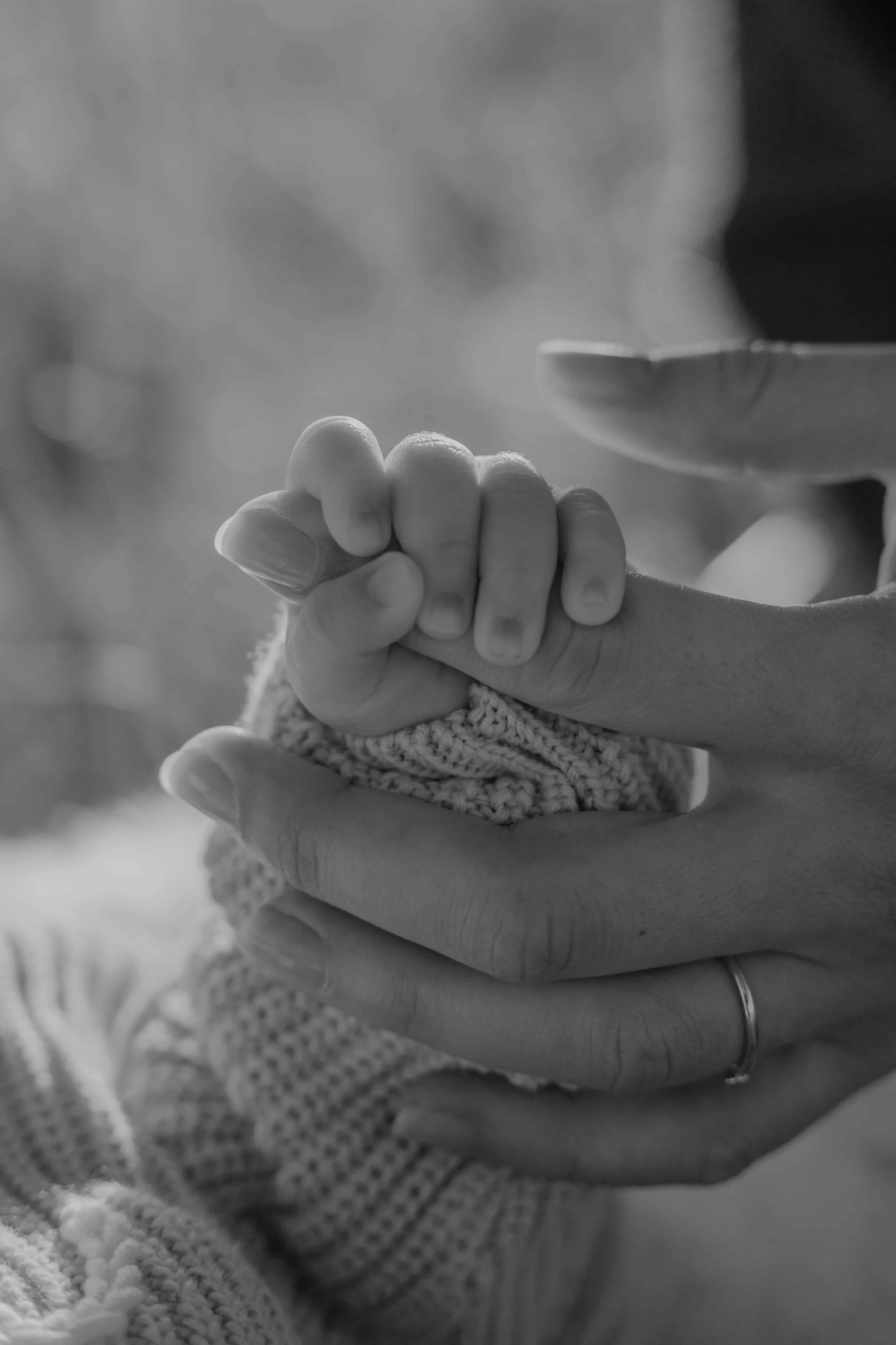 Emotionale und authentische Neugeborenen Fotografie – Nahaufnahme von den kleinen Händchen, die nach der Hand der Mutter greifen.