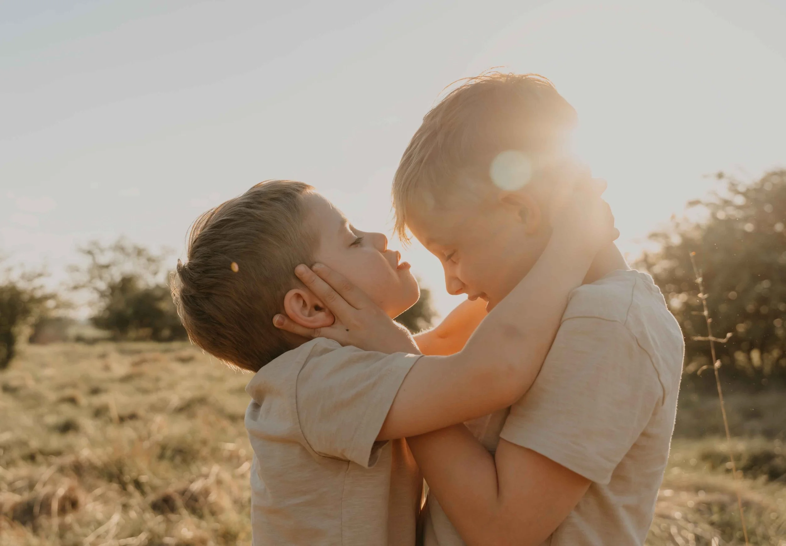 Familienfotografie Kassel – Geschwister umarmen sich auf einer Blumenwiese.