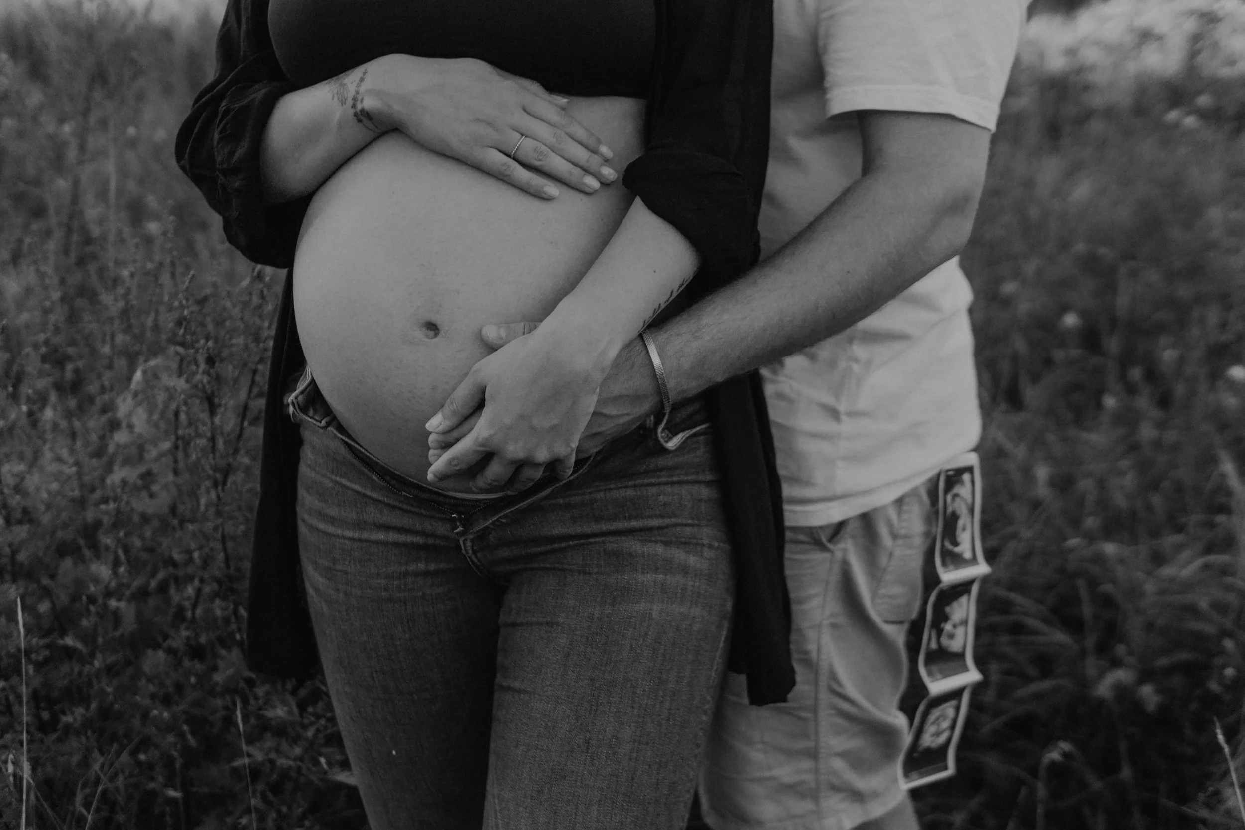 Babybauchshooting Hamburg – werdende Eltern hält zärtlich den BabyBauch und das Ultraschallbild im Sonnenuntergang.