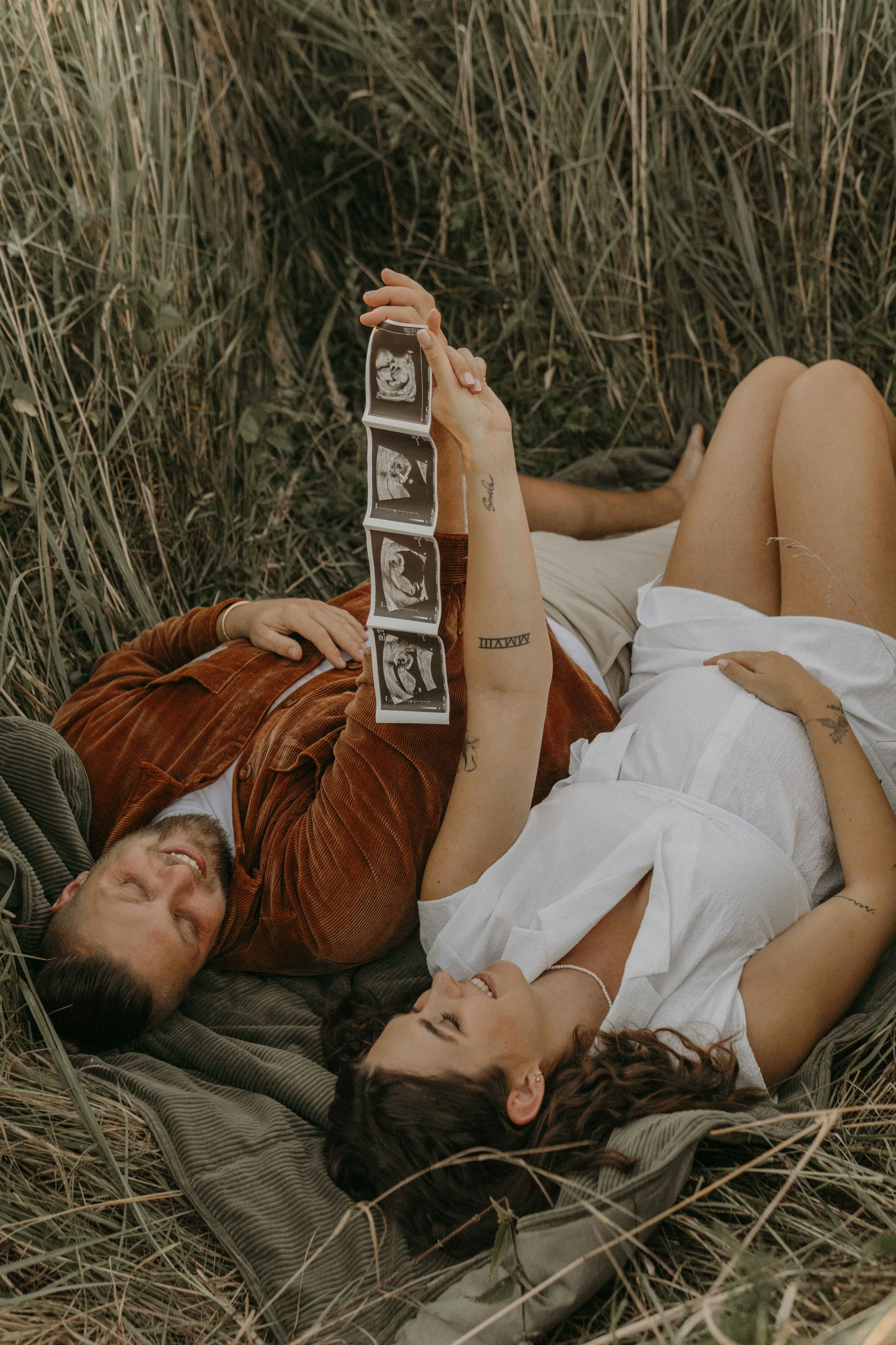 Babybauchshooting Hamburg – werdende Elternhalten Ultraschallbild hoch im Sonnenuntergang.