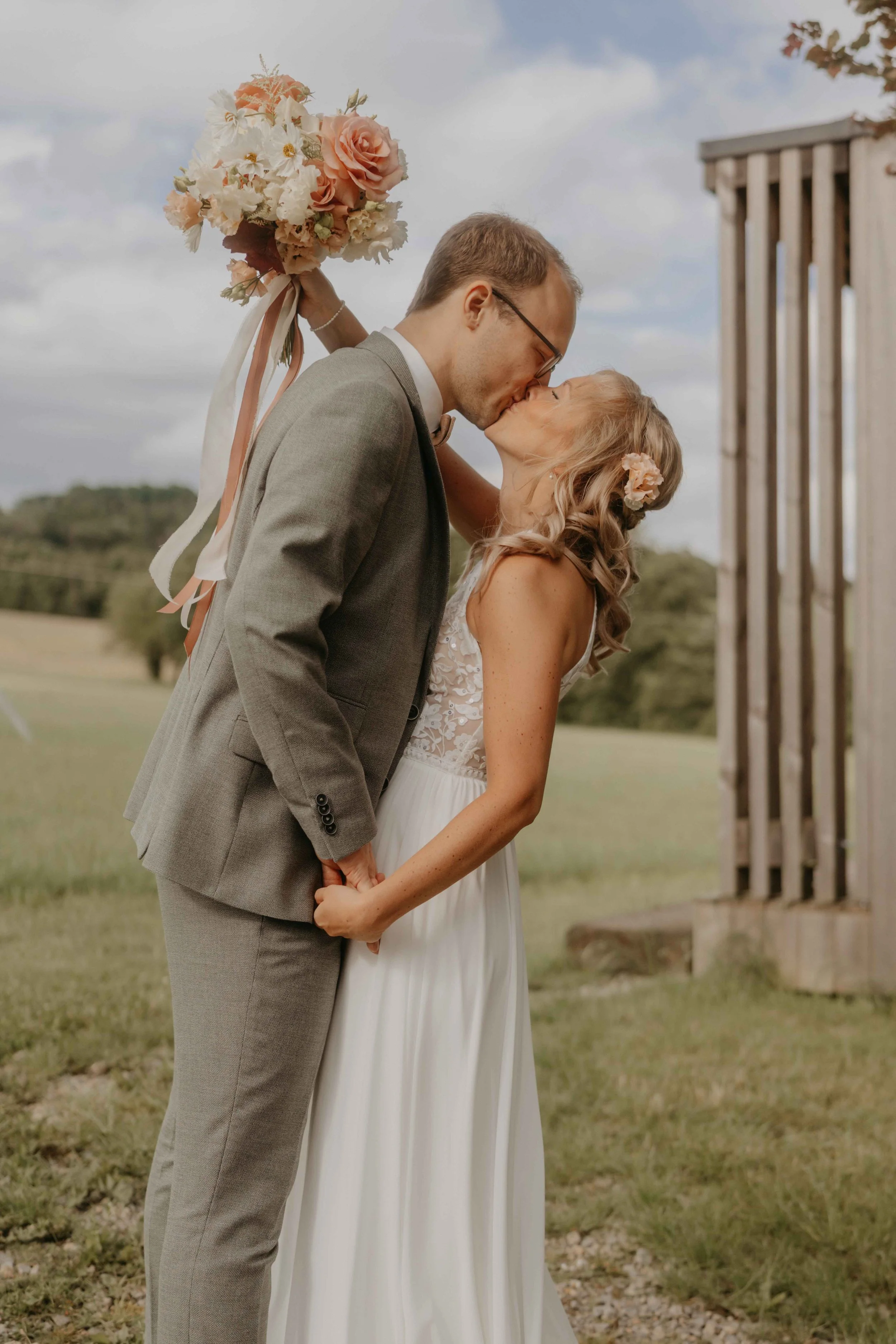 Braut und Bräutigam stehen eng umschlungen in der Wiese, natürliche Paarfotografie.