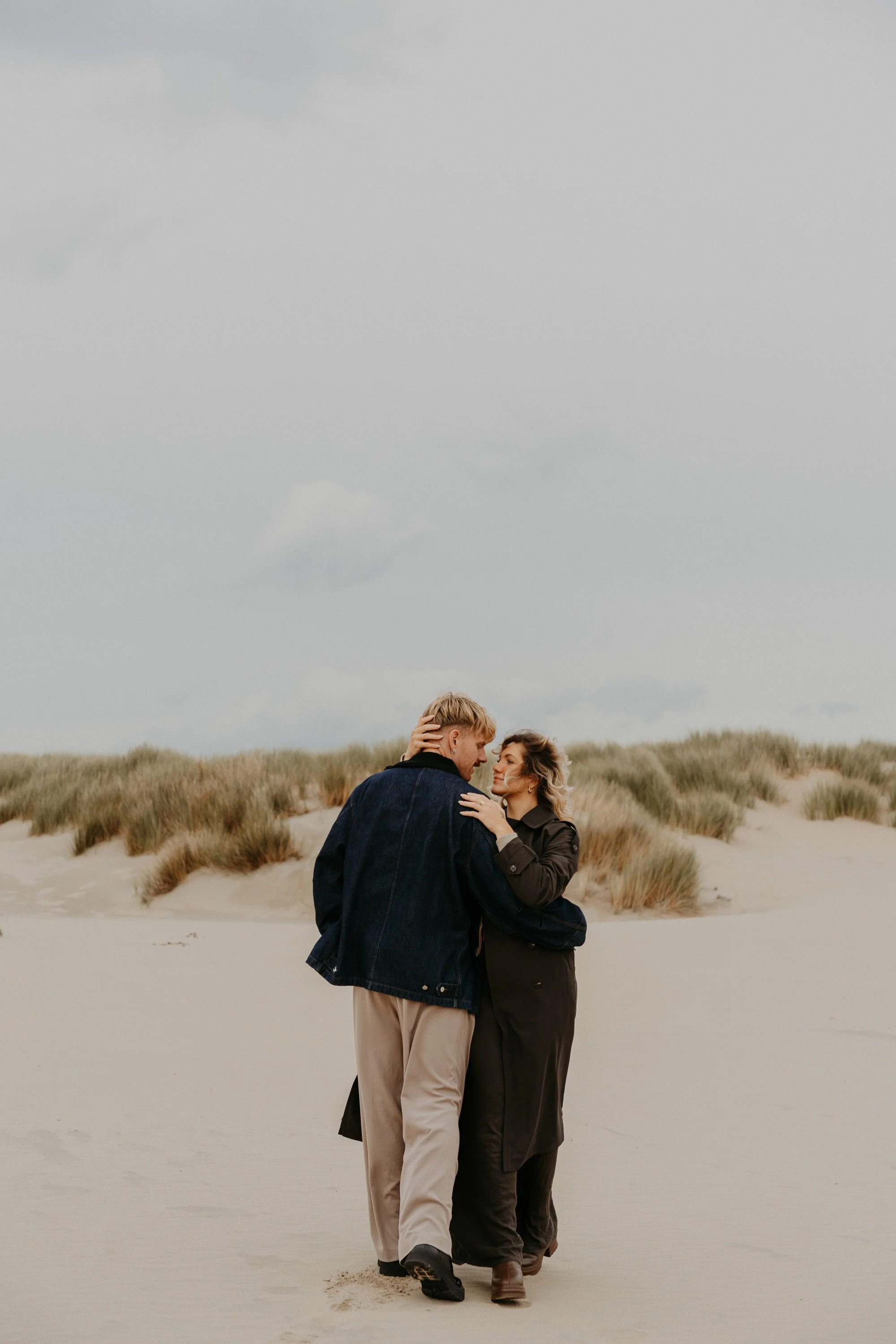 Authentische Paarfotografie Holland – verliebter Blick zwischen Dünen und Meer.