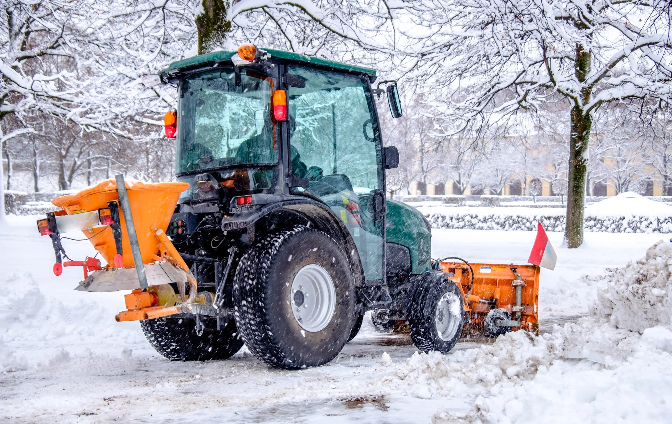 Ein Schneepflug fährt auf einer verschneiten Straße im Winter, um den Weg freizuräumen.
