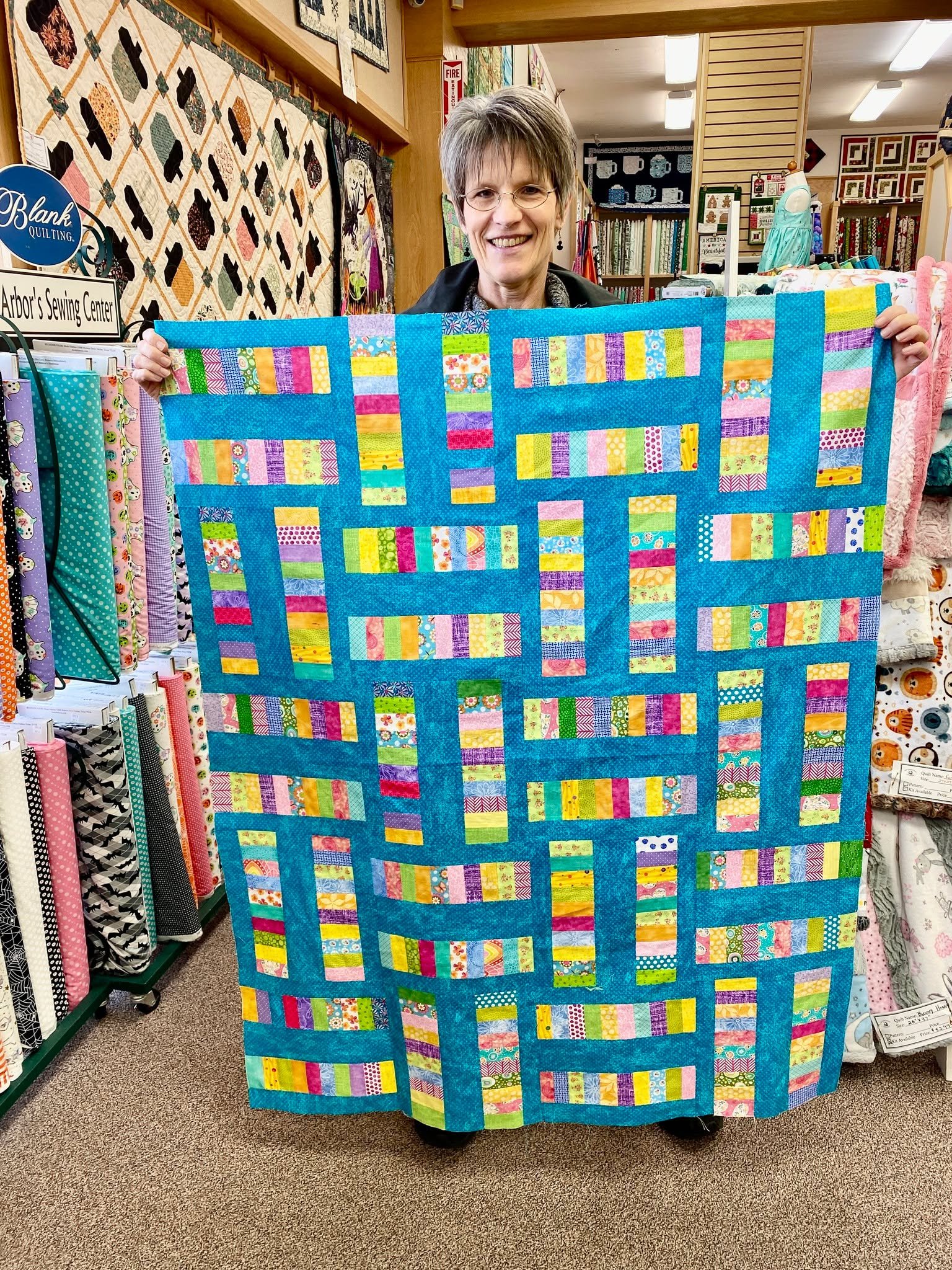 Sheryl stopped in the other day to find a backing for this bright and shiny scrappy quilt she made by creating her own pattern inspired by something she saw and loved. We LOVED her use of vibrant small prints and Sheryl did find her perfect match. 🩷
