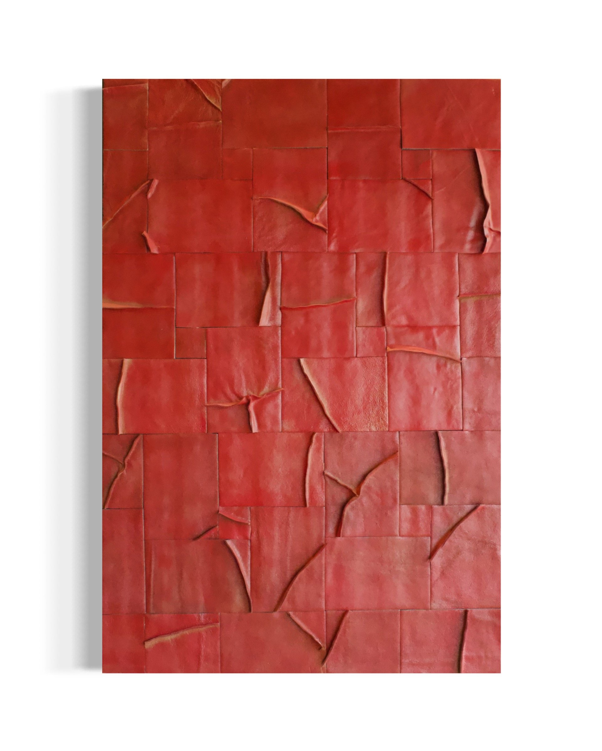 Close-up of a red, textured surface with uneven, overlapping pieces that have a crumpled appearance, resembling leather or painted material.